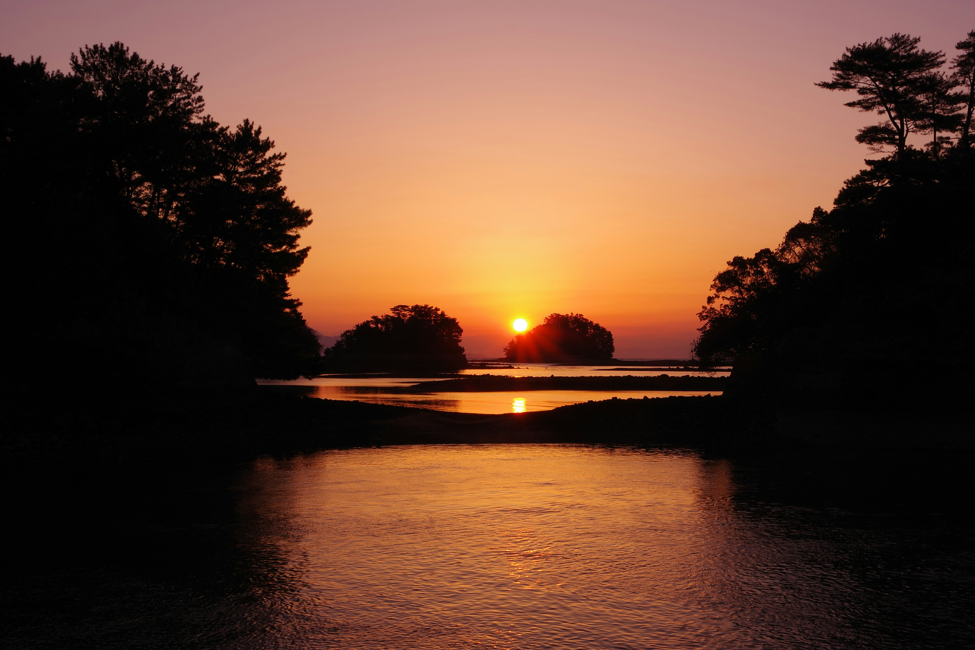 Serene sunset over calm waters with silhouetted islands