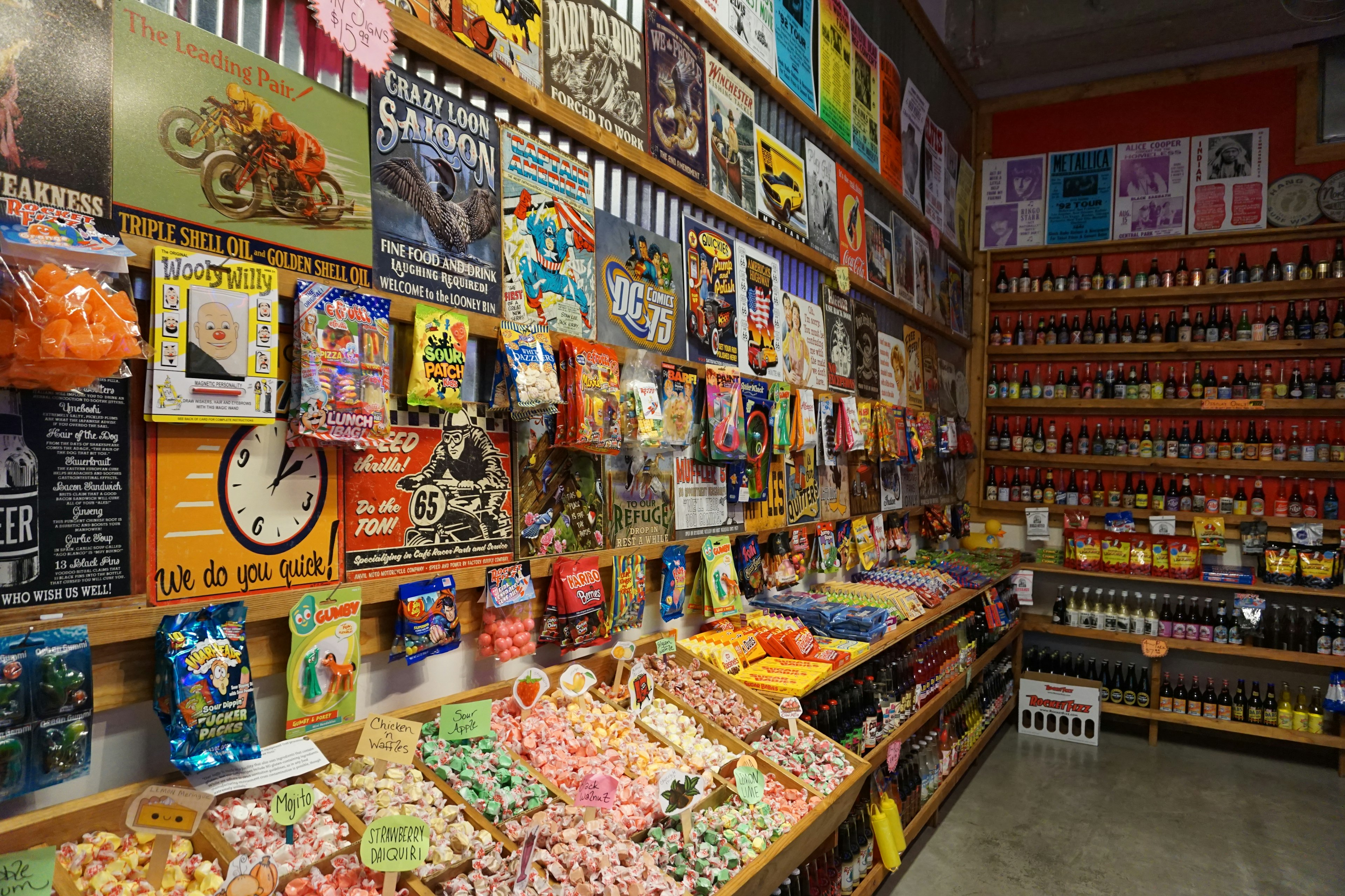 Interior toko snack penuh dengan permen berwarna-warni dan poster