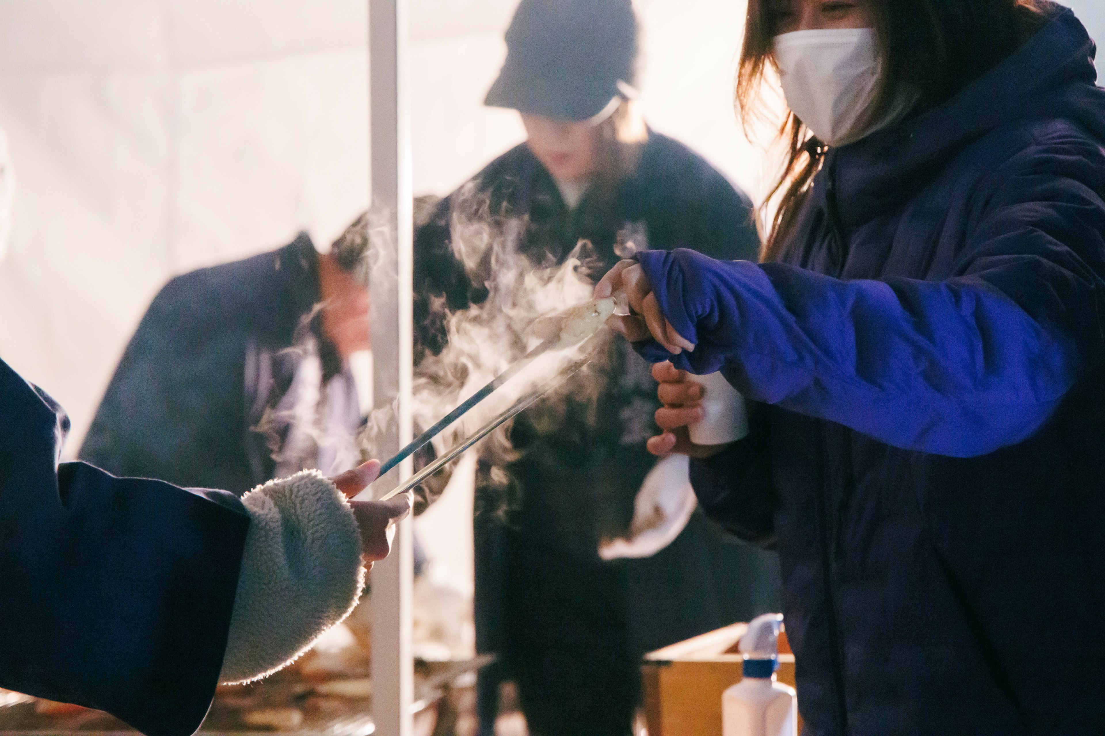 A woman receiving food at an outdoor stall holding a steaming item