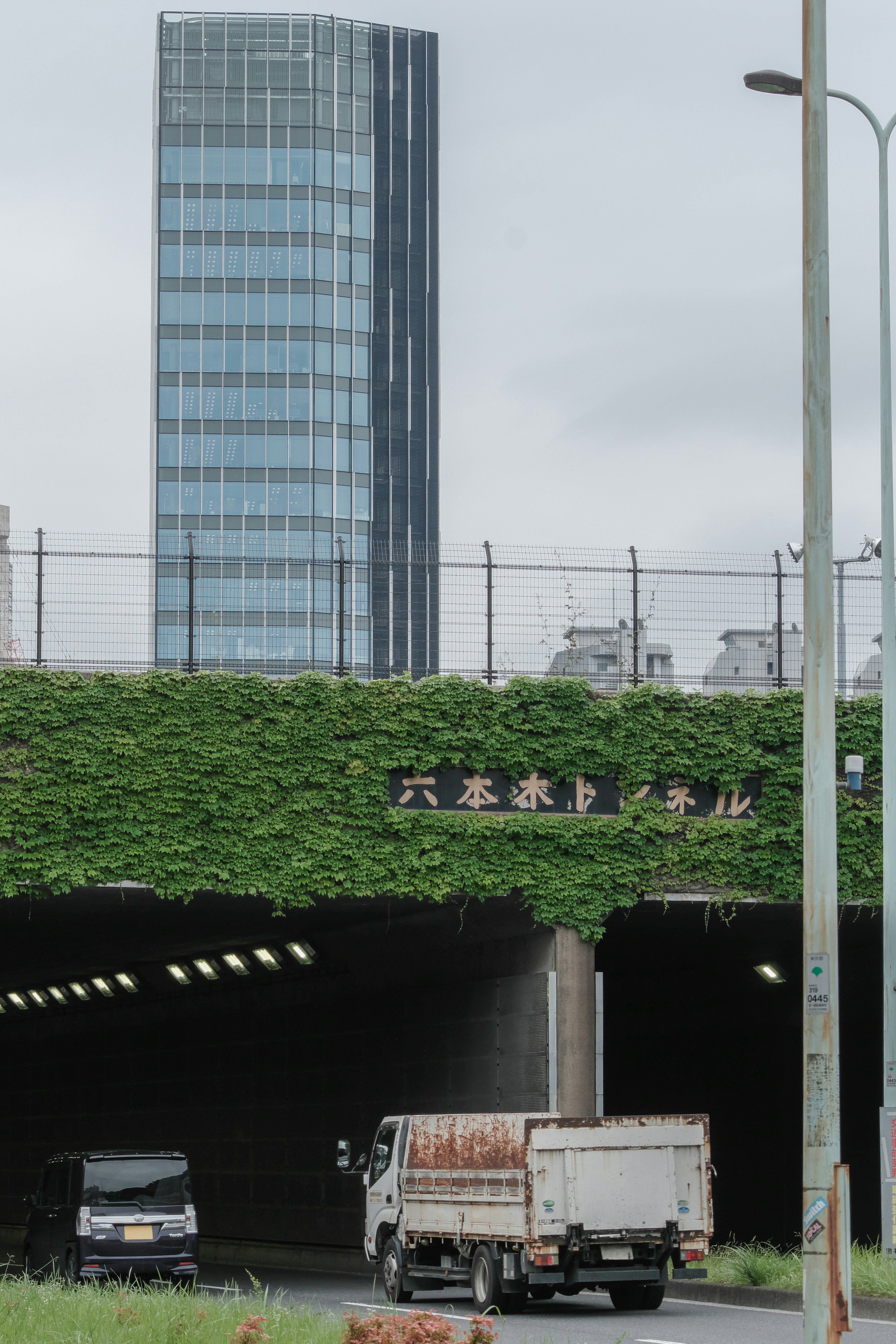 Un edificio alto y la entrada de un túnel cubierto de vegetación son visibles