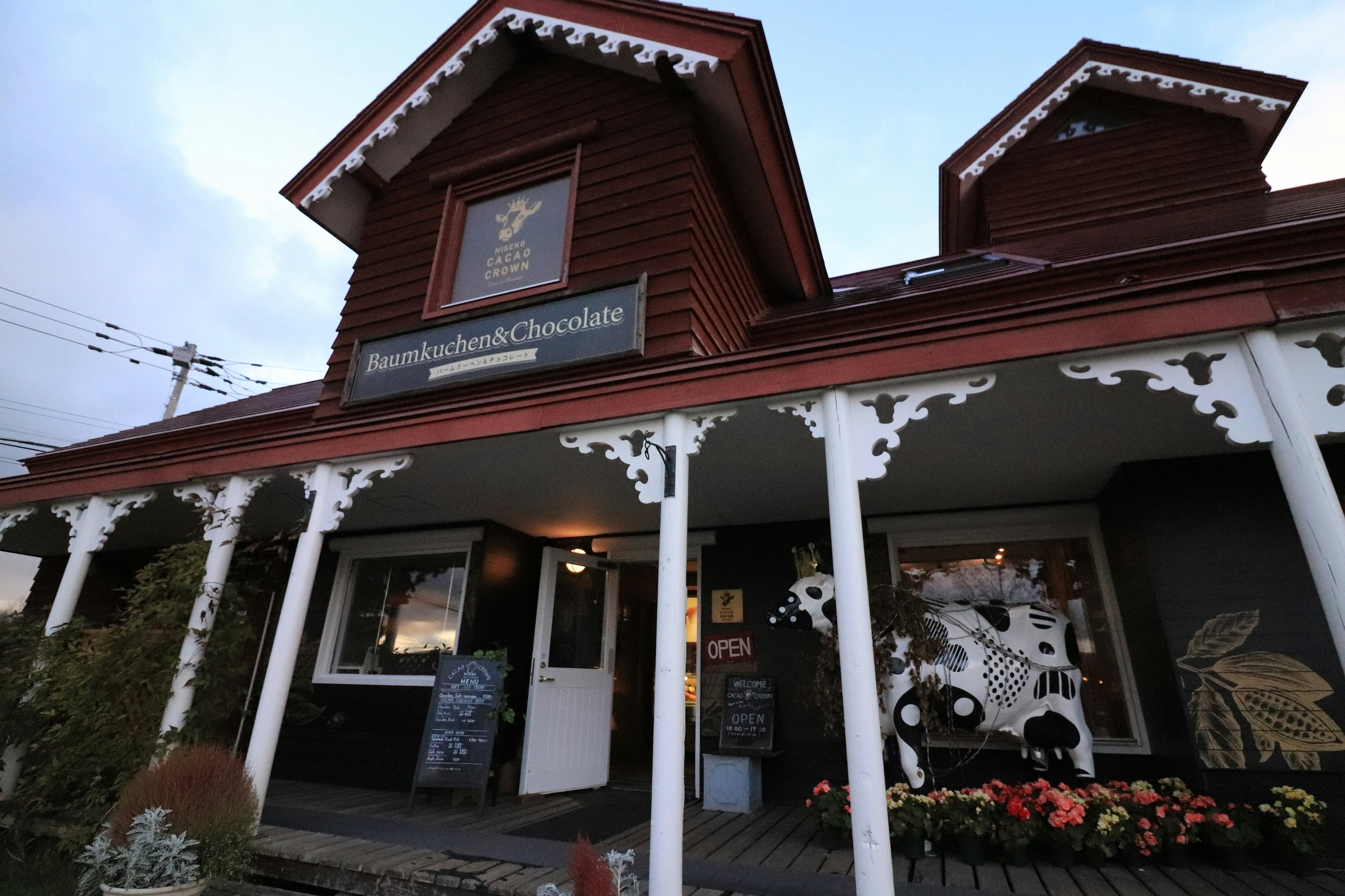 赤い木造の建物の外観に白い柱と装飾があり 店名の看板が目立つ