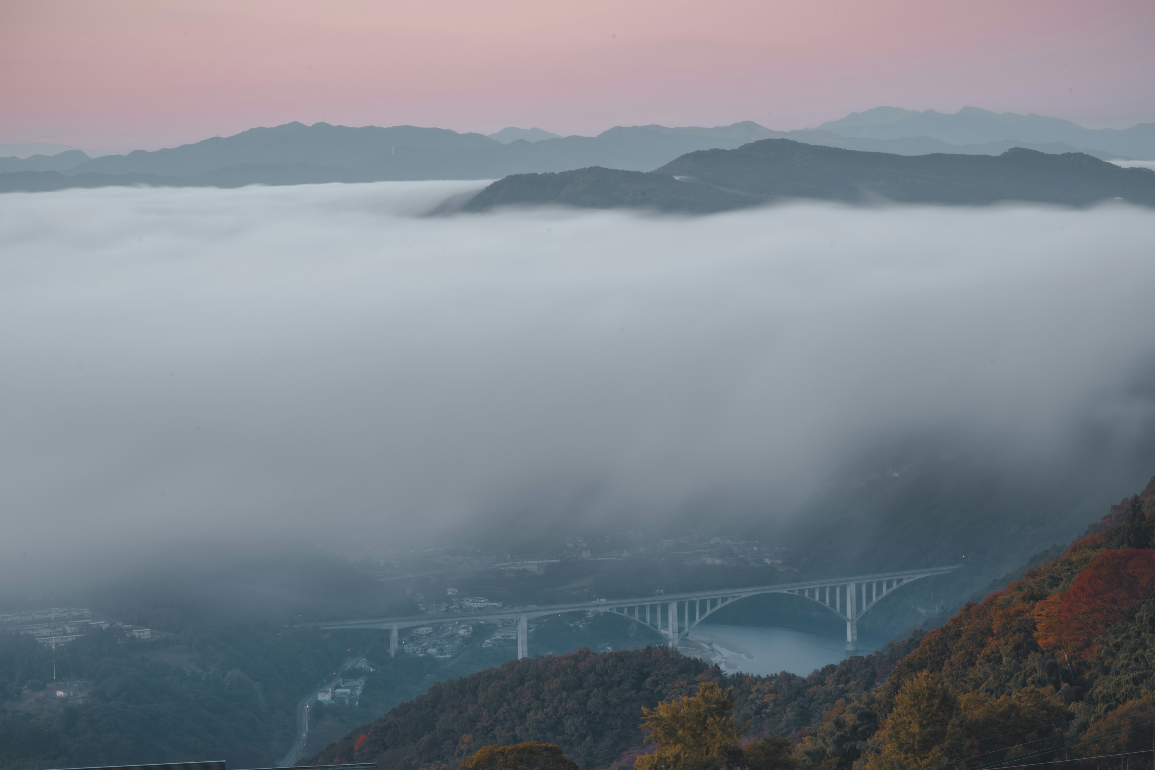 Vista escénica de montañas y un puente envuelto en niebla