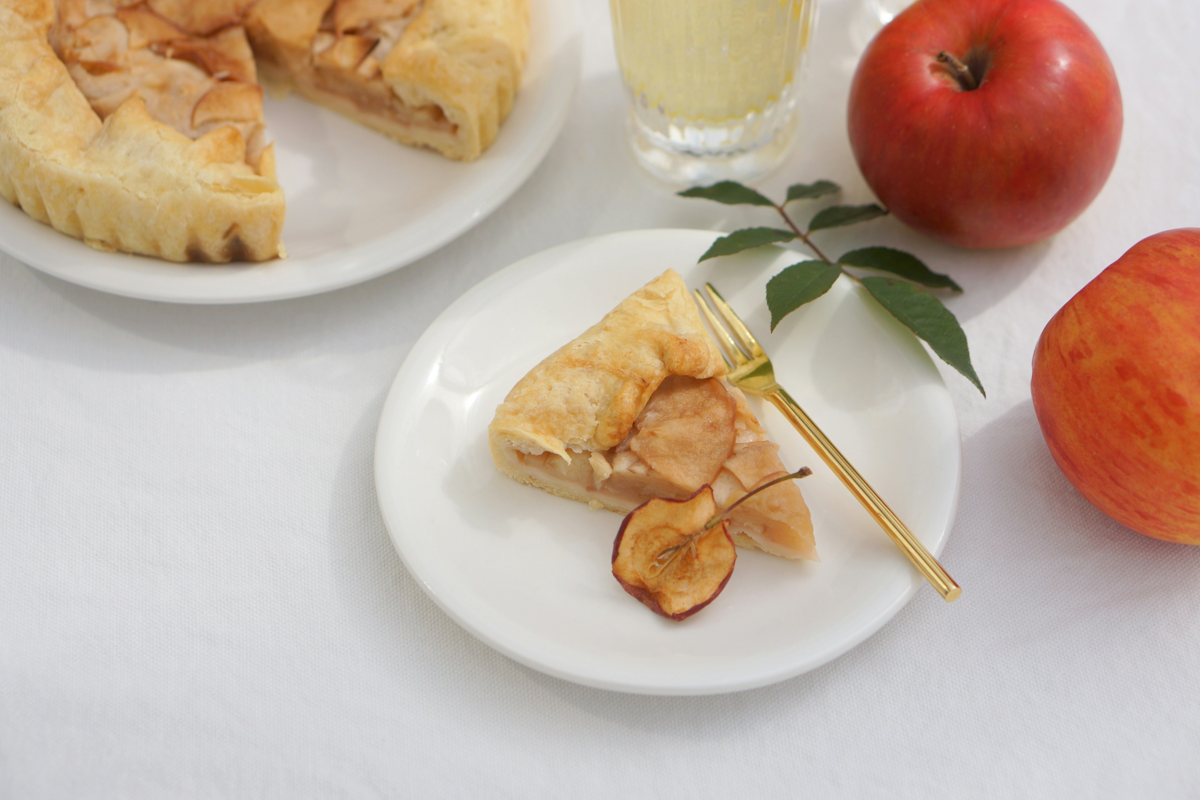 Une belle mise en scène de table avec une tarte aux pommes et des pommes en tranches