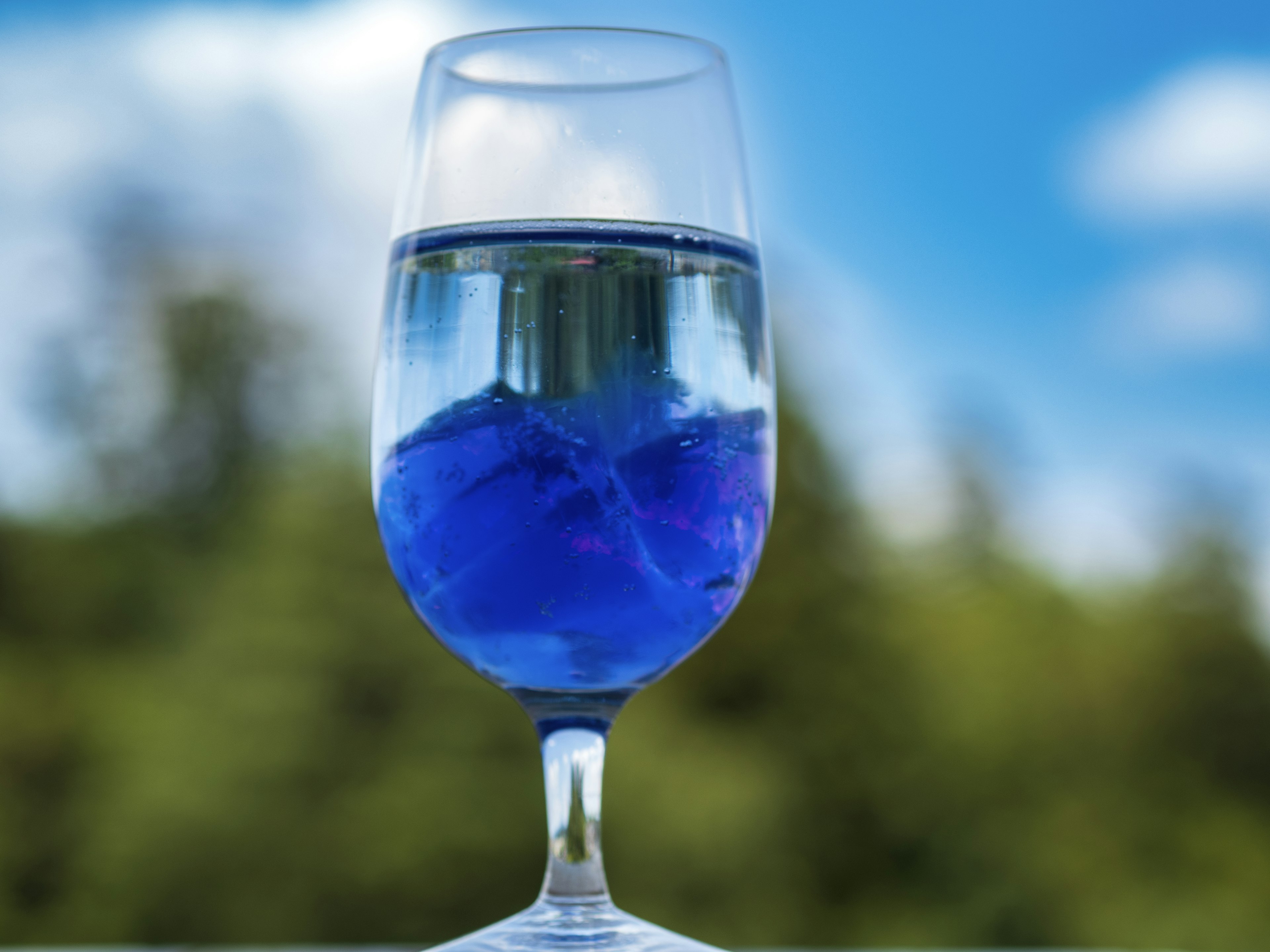 Ein Glas Wasser mit blauem Eis und klarem blauen Himmel