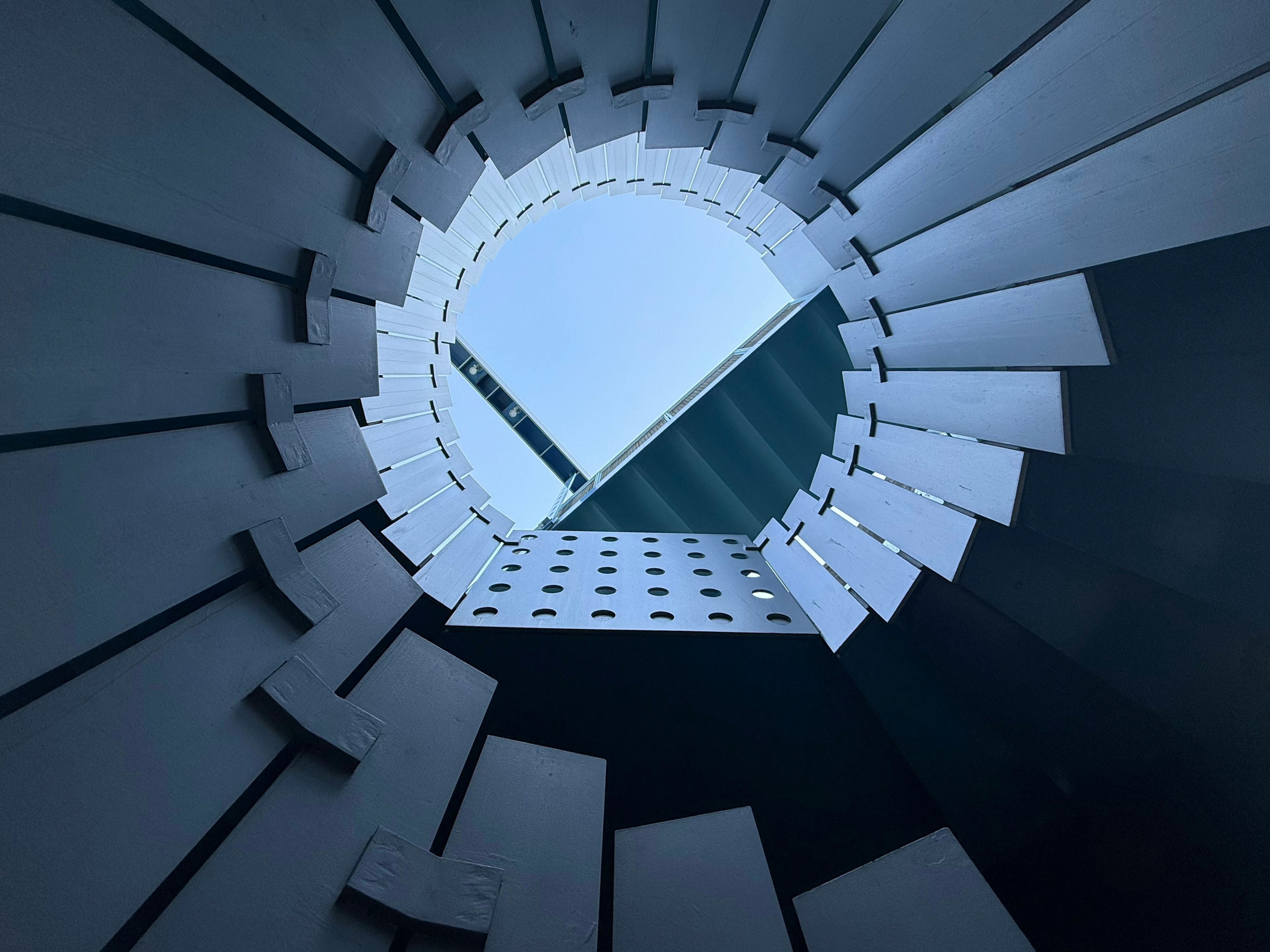 View looking up through a circular structure revealing blue sky