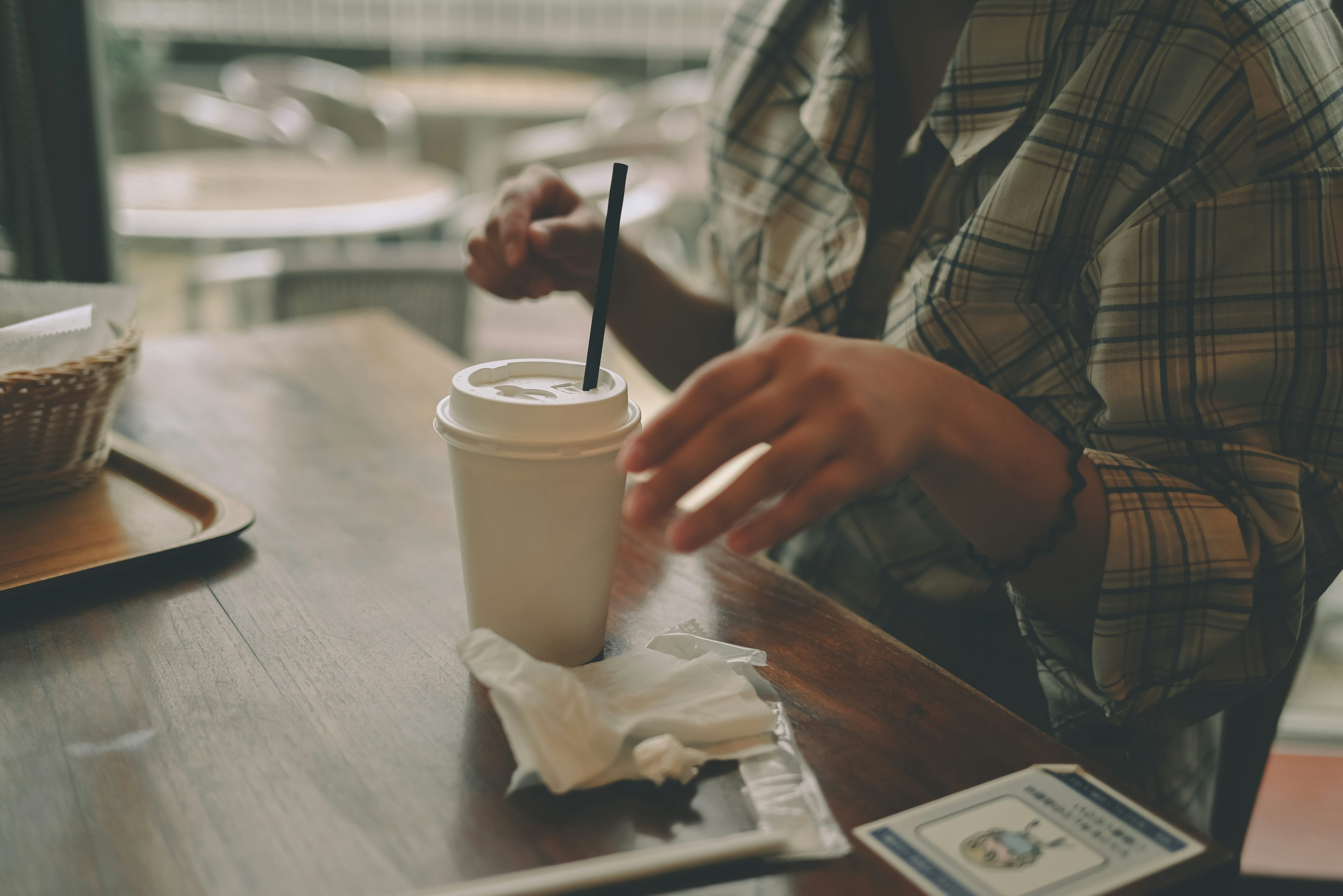 Une main atteignant une tasse de café sur une table en bois