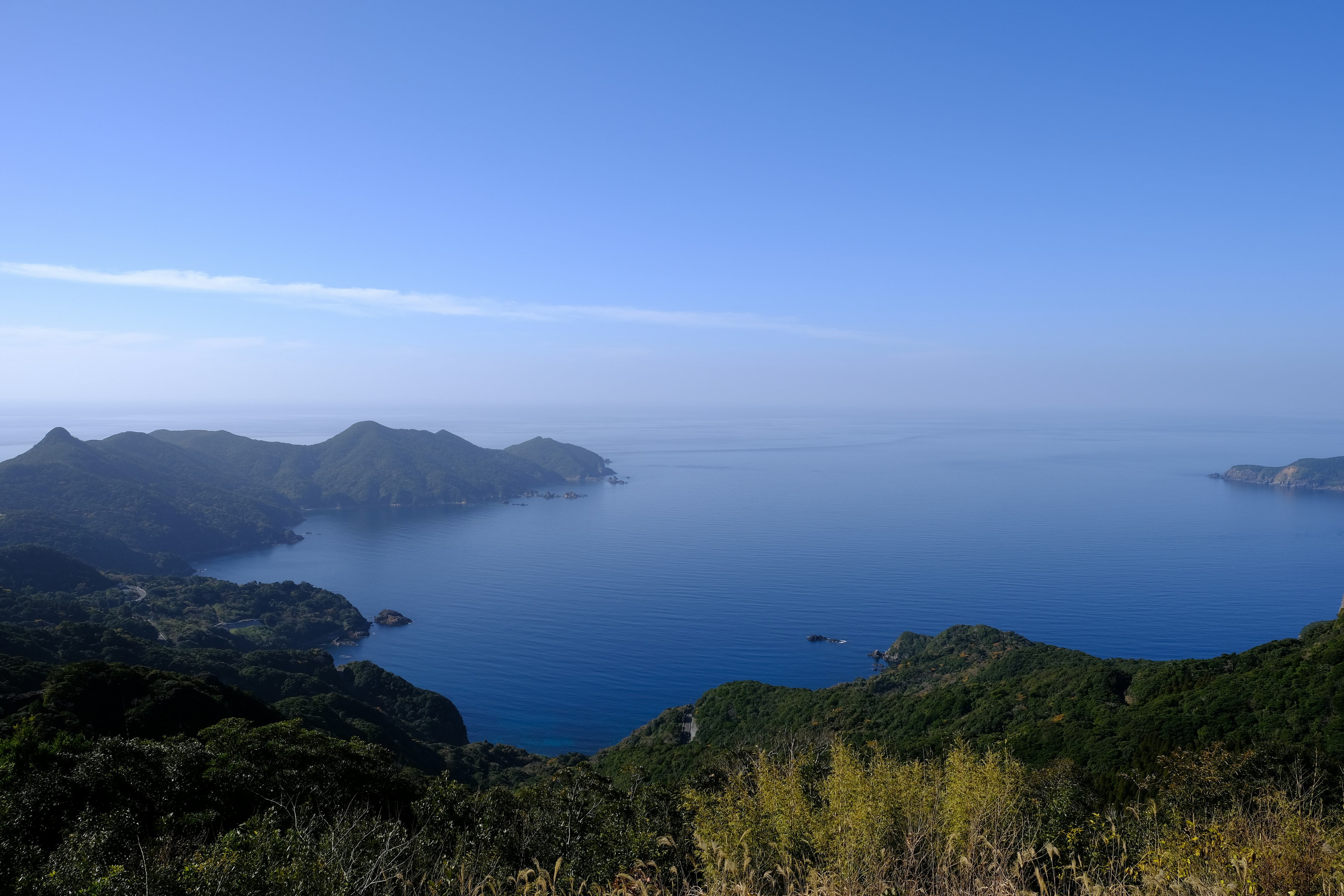 藍色海洋和山脈的風景在晴朗的天空下