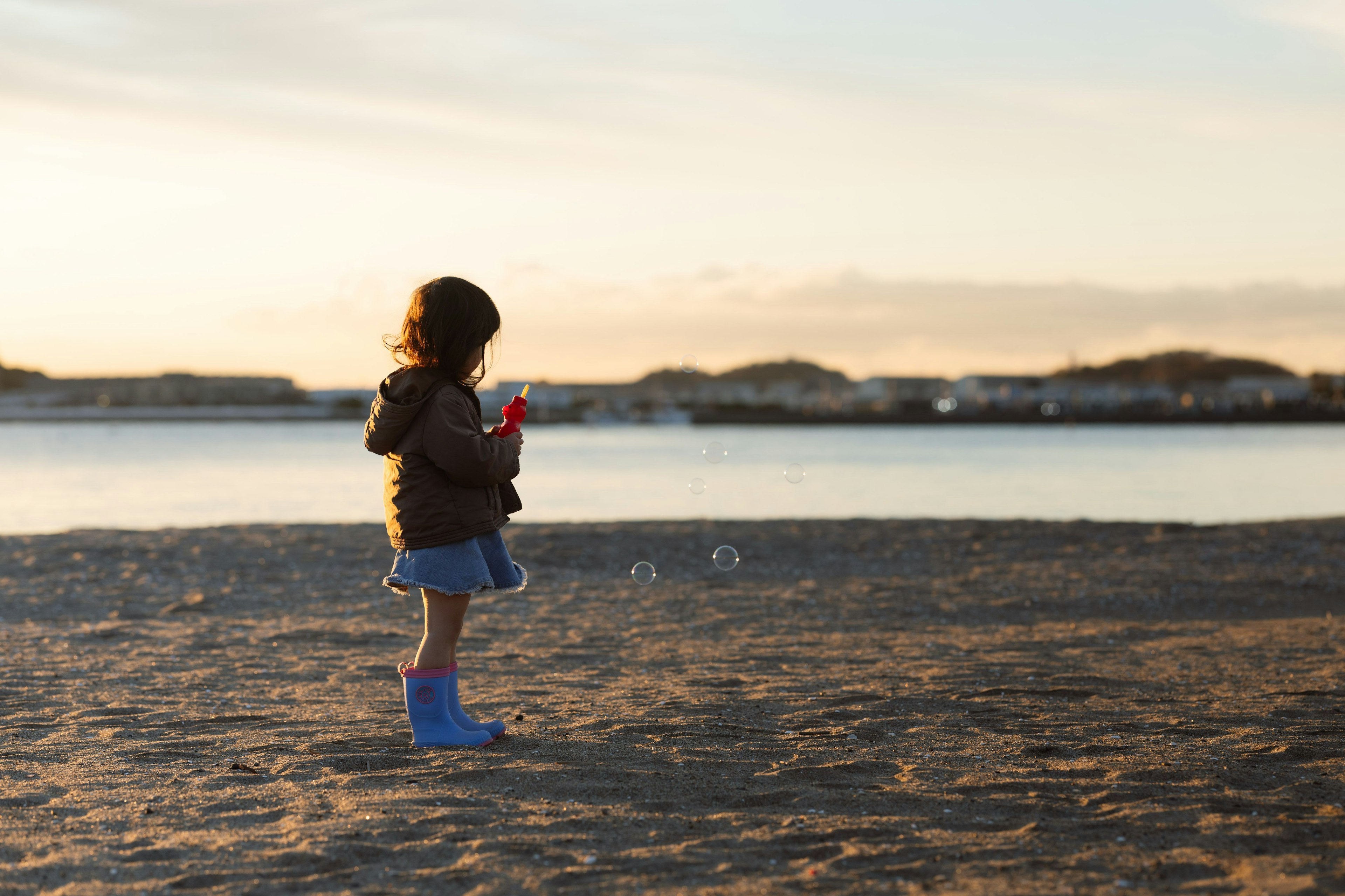 夕日を背景に砂浜で遊ぶ子供のシルエット