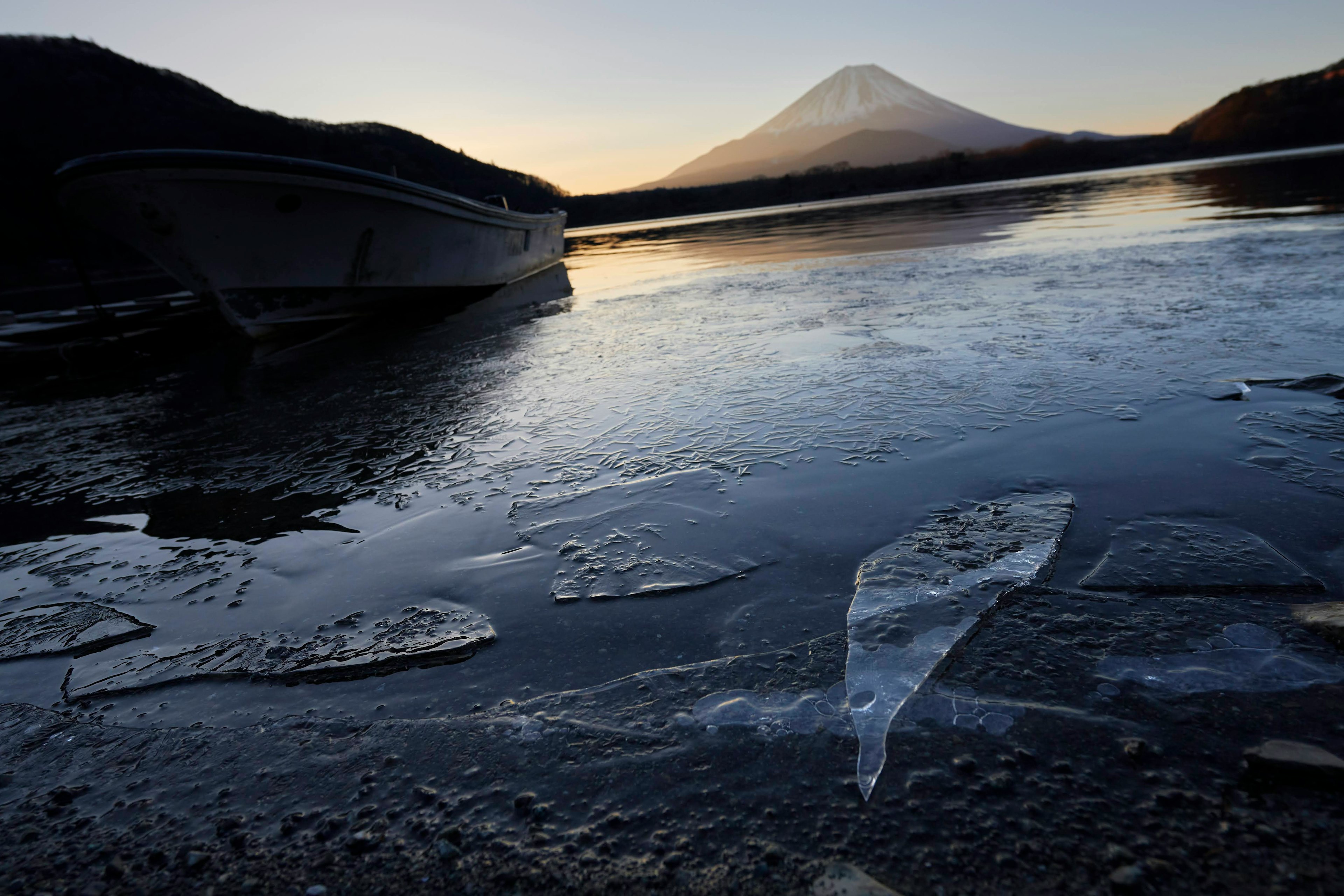 富士山が背景にある凍った湖とボートの風景