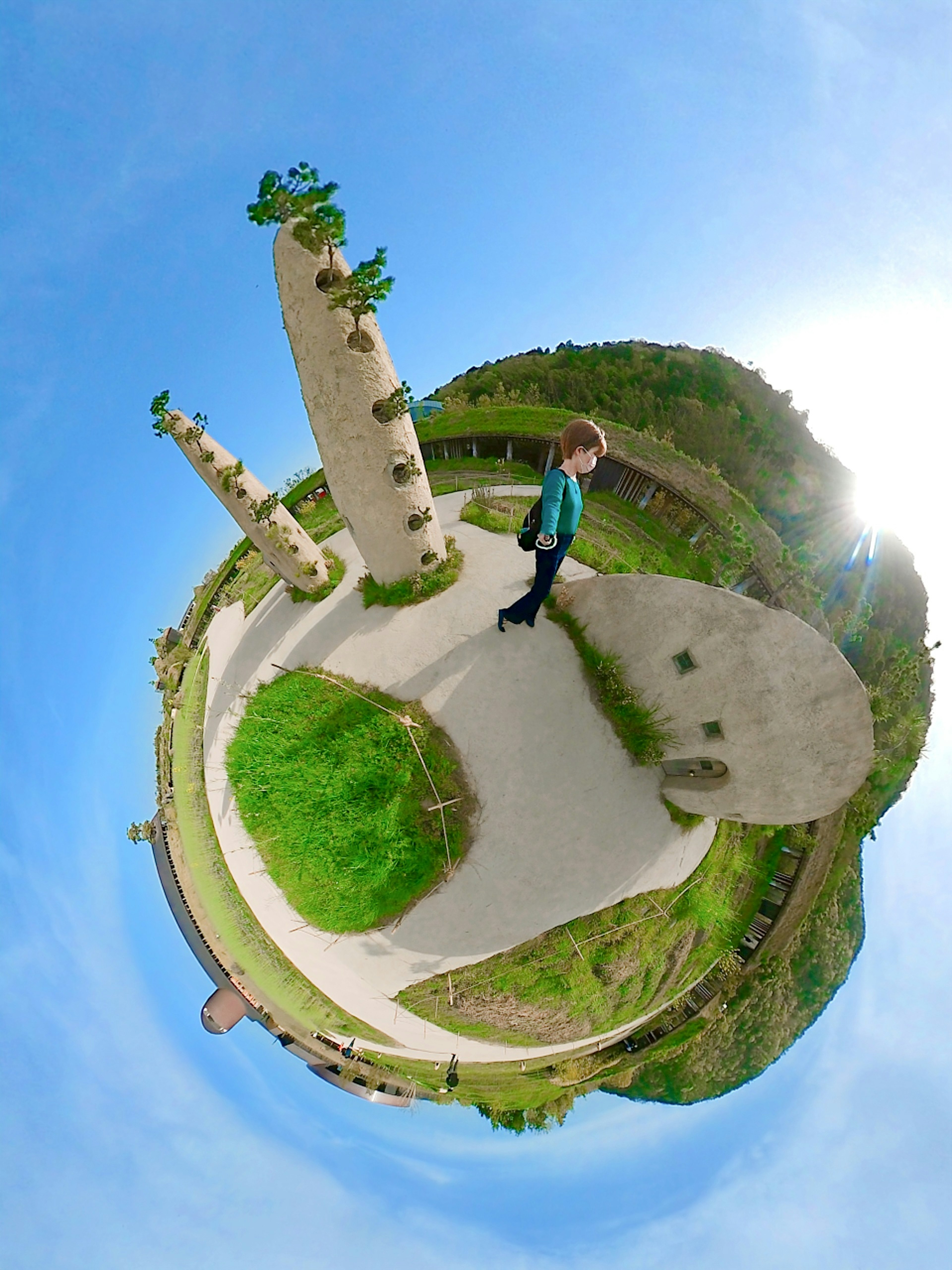 Un bambino in piedi sotto un cielo blu con un paesaggio verde in una vista panoramica