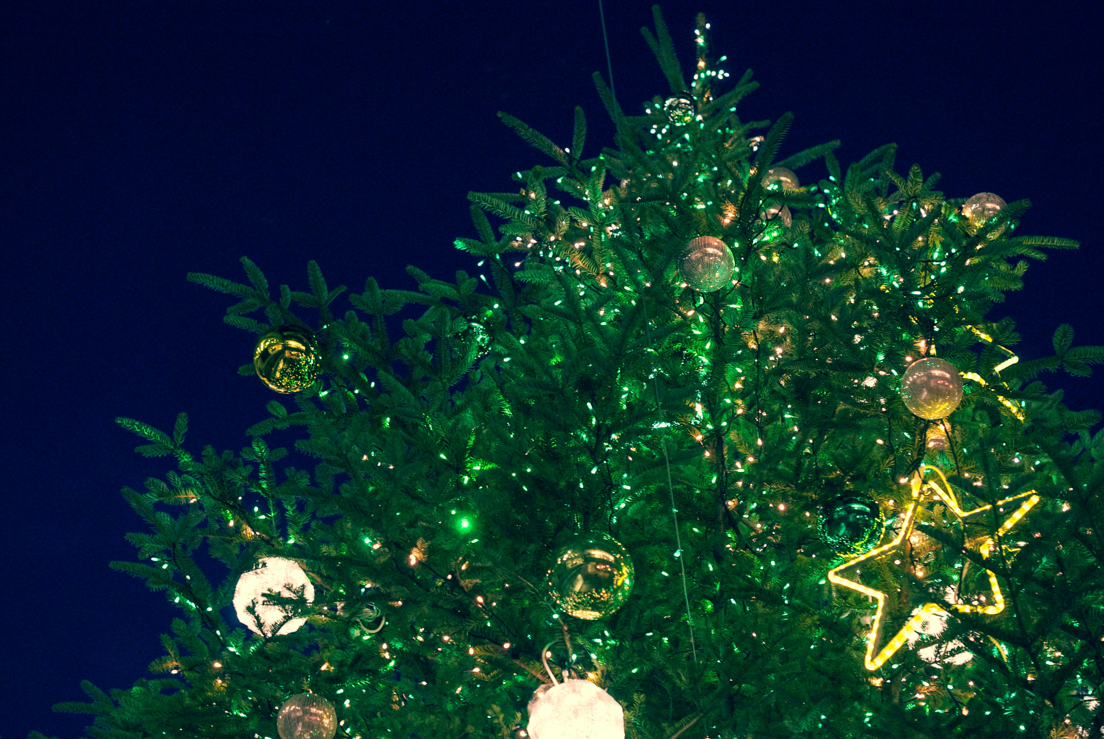 Decorated Christmas tree top with sparkling ornaments and green foliage