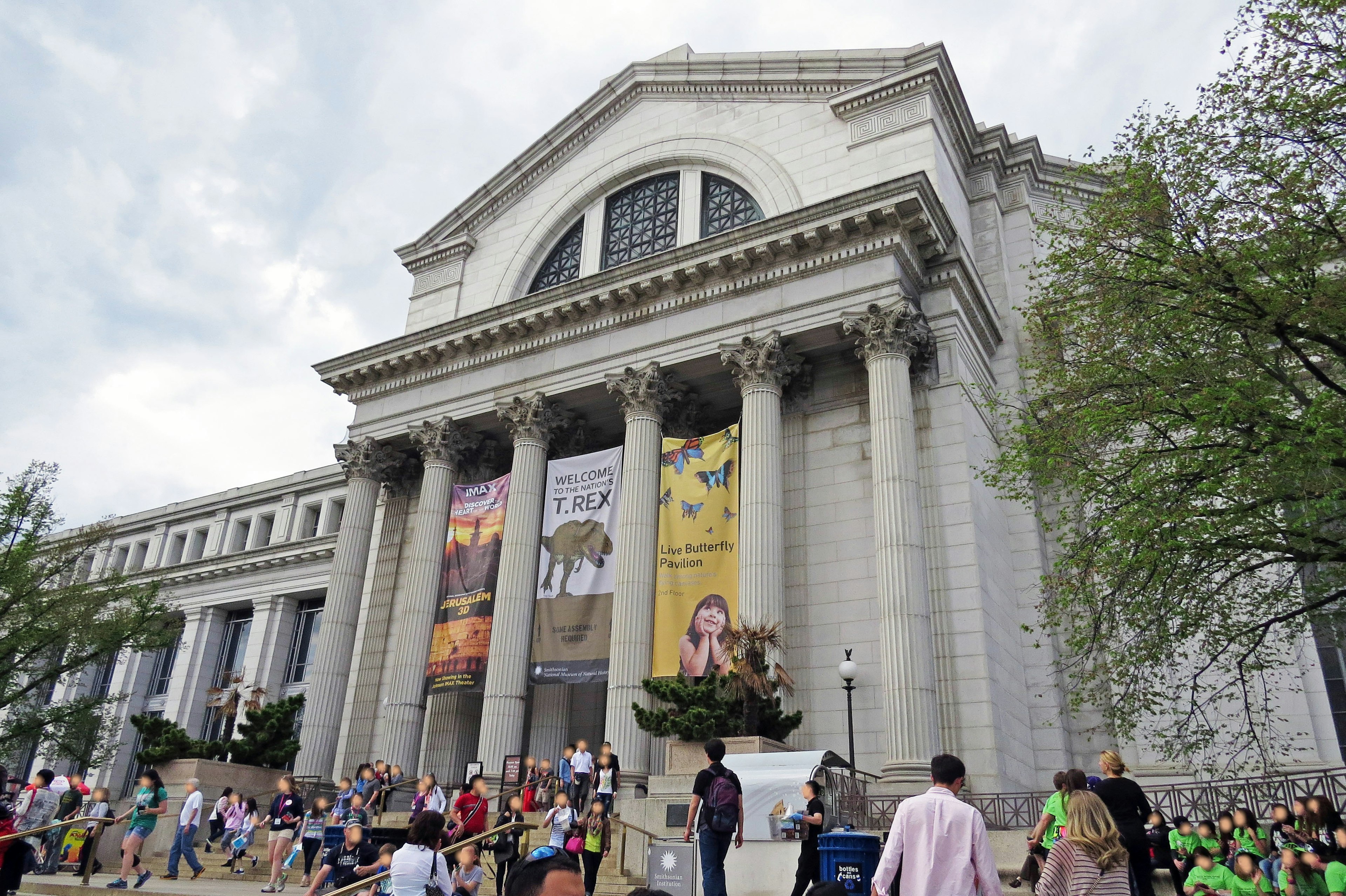 Exterior view of a museum with large columns and exhibition banners Many people are visiting