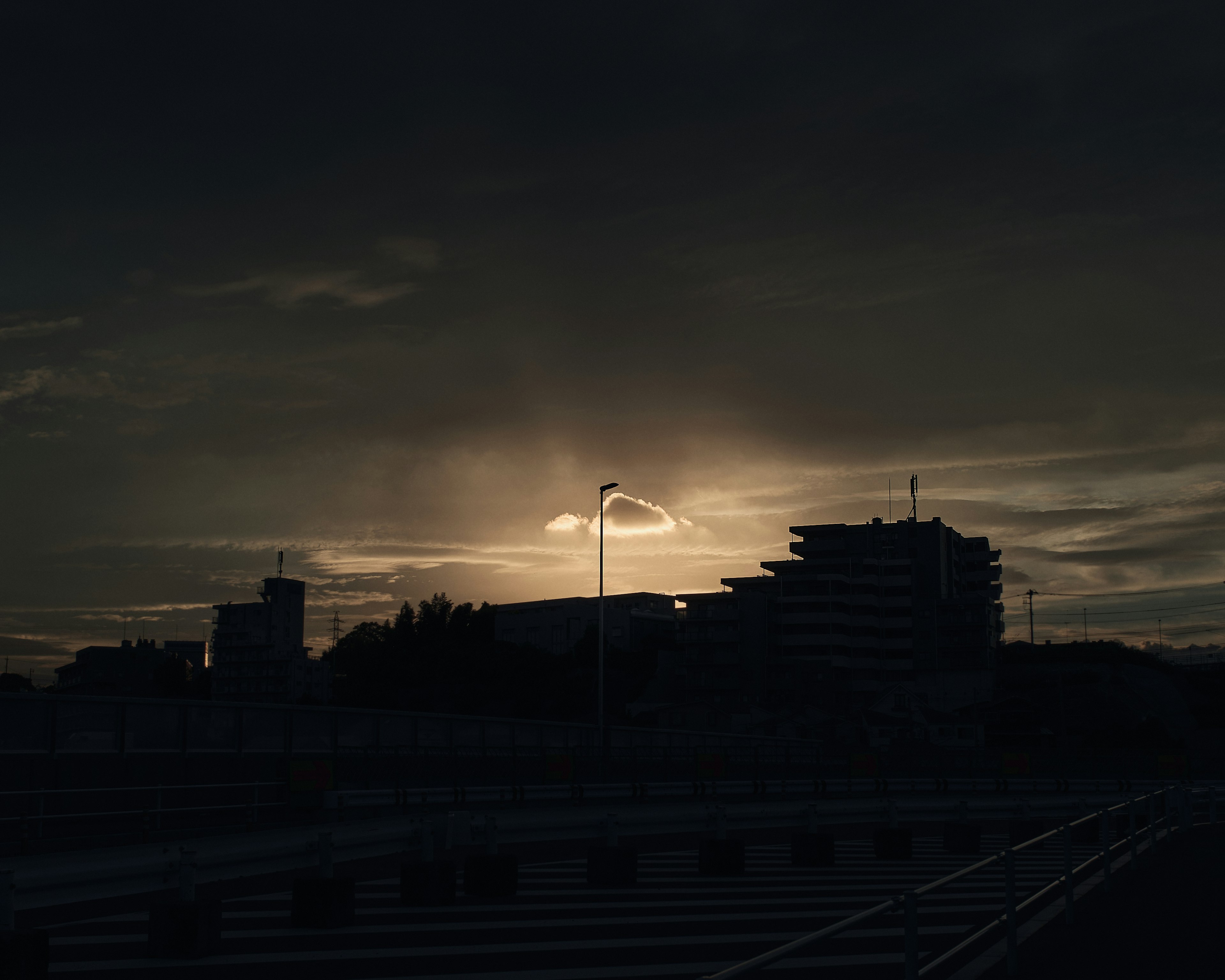 Silhouette of buildings against a dark sky at sunset