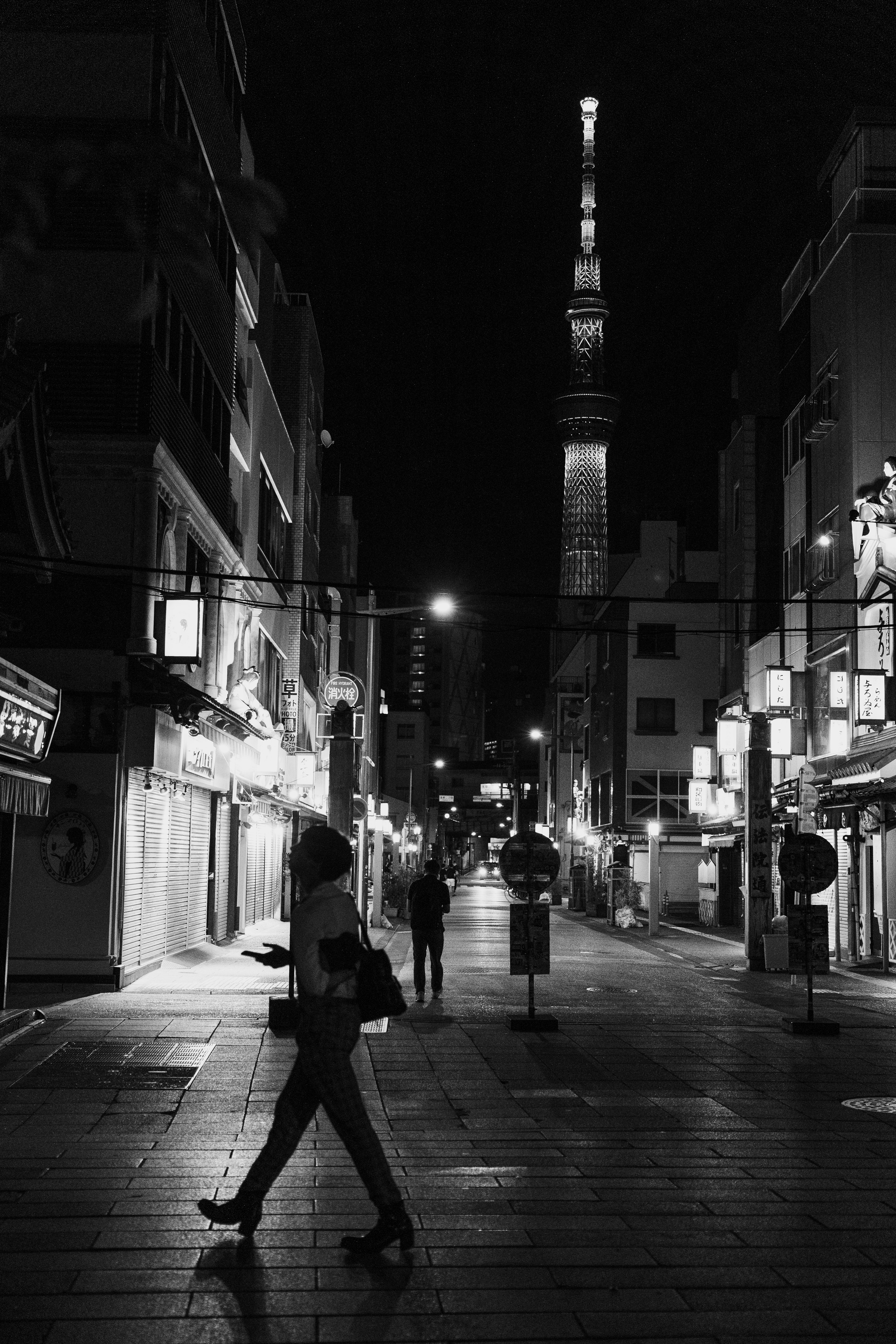 Silhouette einer Person, die nachts in einer Straße in Tokio mit dem Tokyo Tower im Hintergrund geht