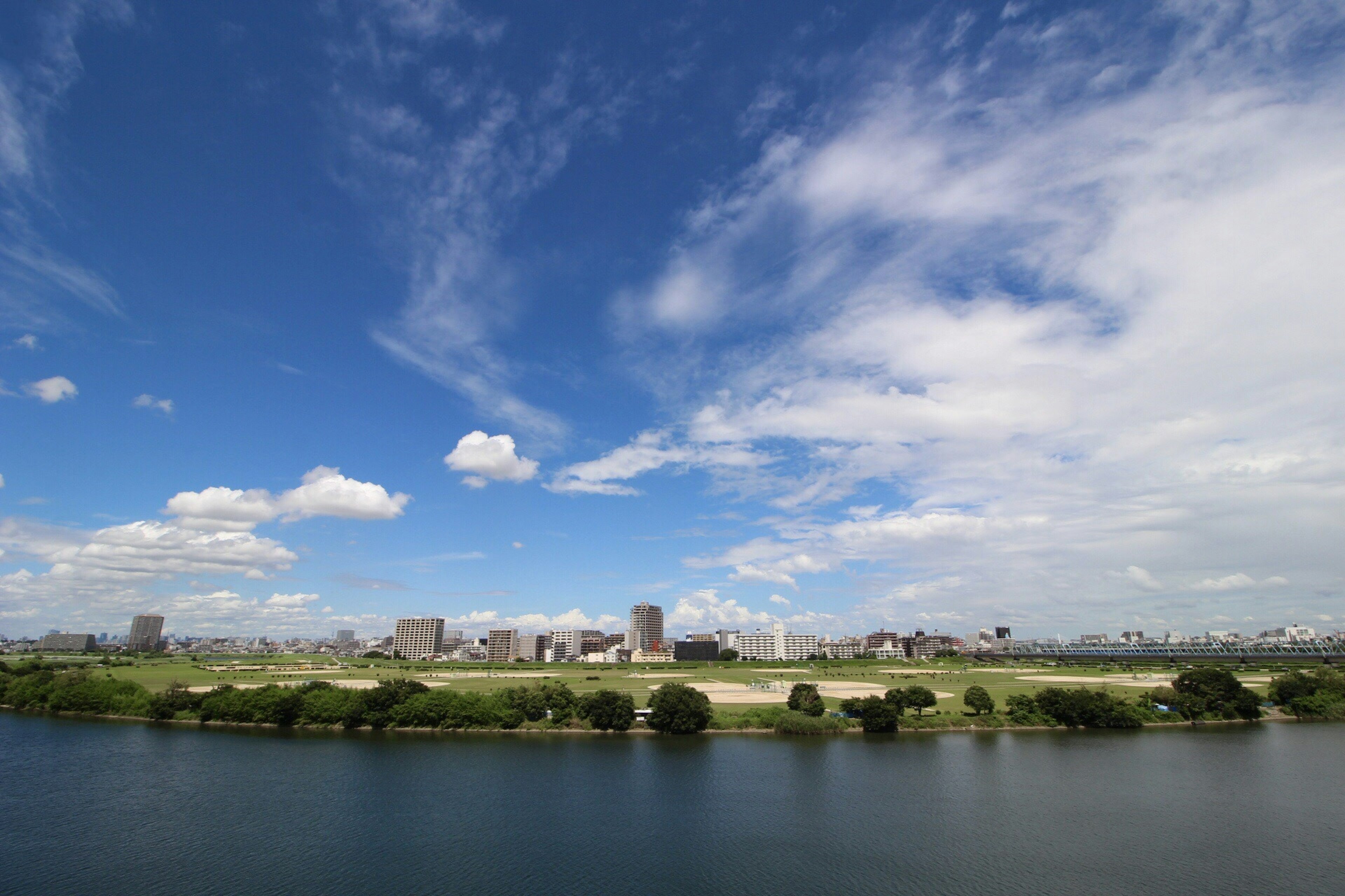 青空と雲が広がる川の風景と都市のシルエット