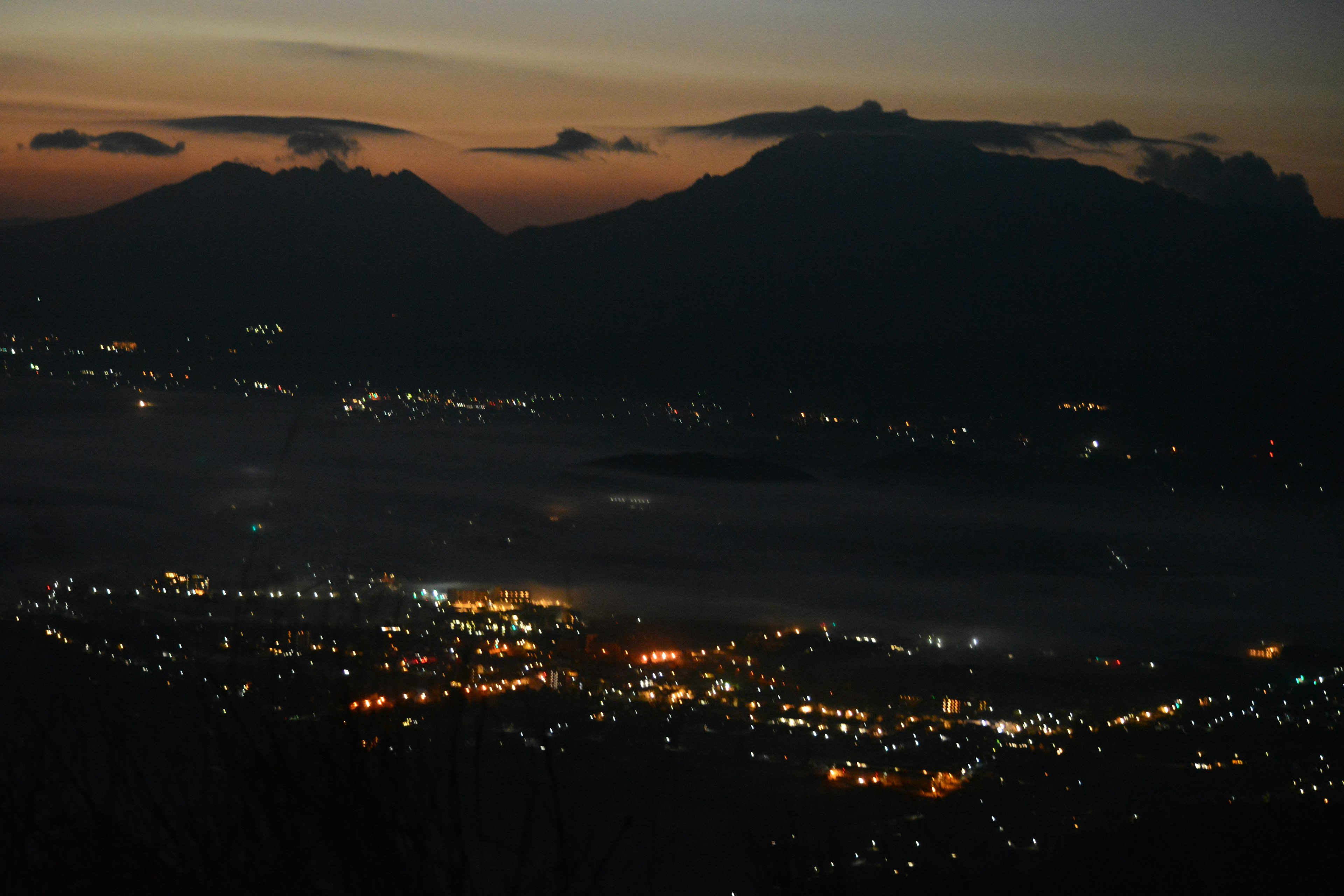 Vue pittoresque des montagnes et des lumières de la ville au crépuscule