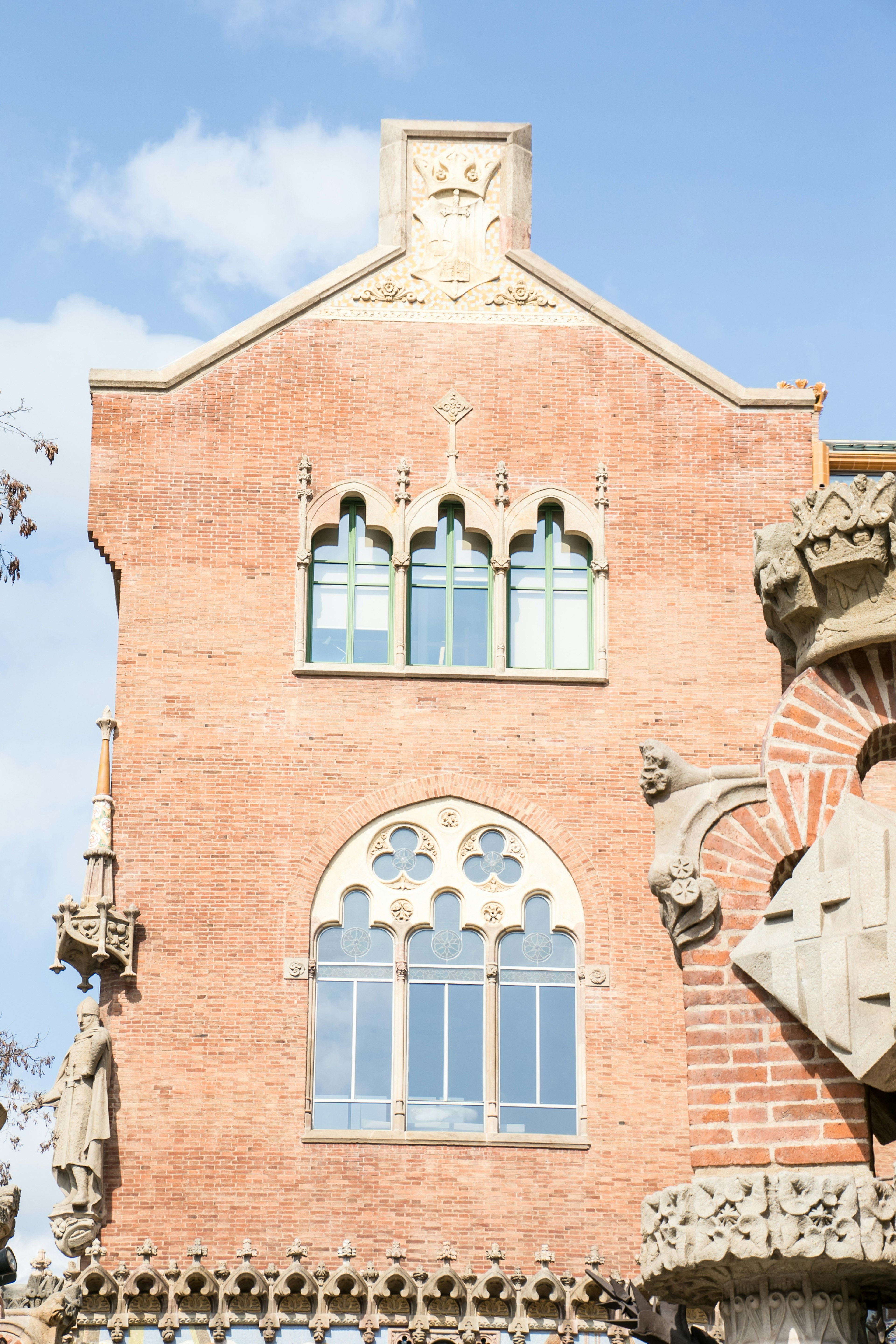 Partie d'un bâtiment en briques rouges avec des fenêtres distinctives et des éléments décoratifs