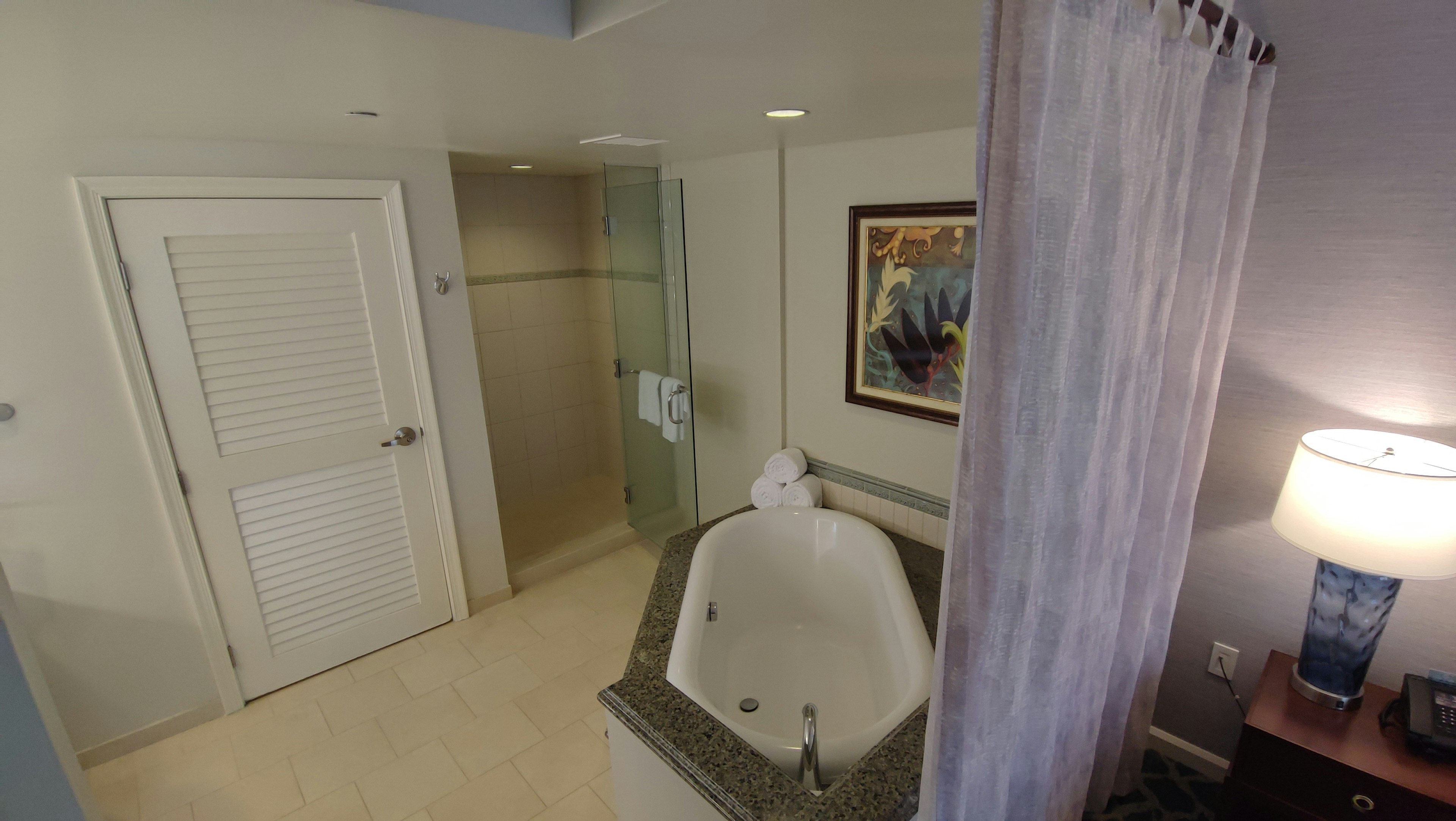 Interior of a bathroom featuring a jacuzzi and shower area Artwork on the wall and a nightstand