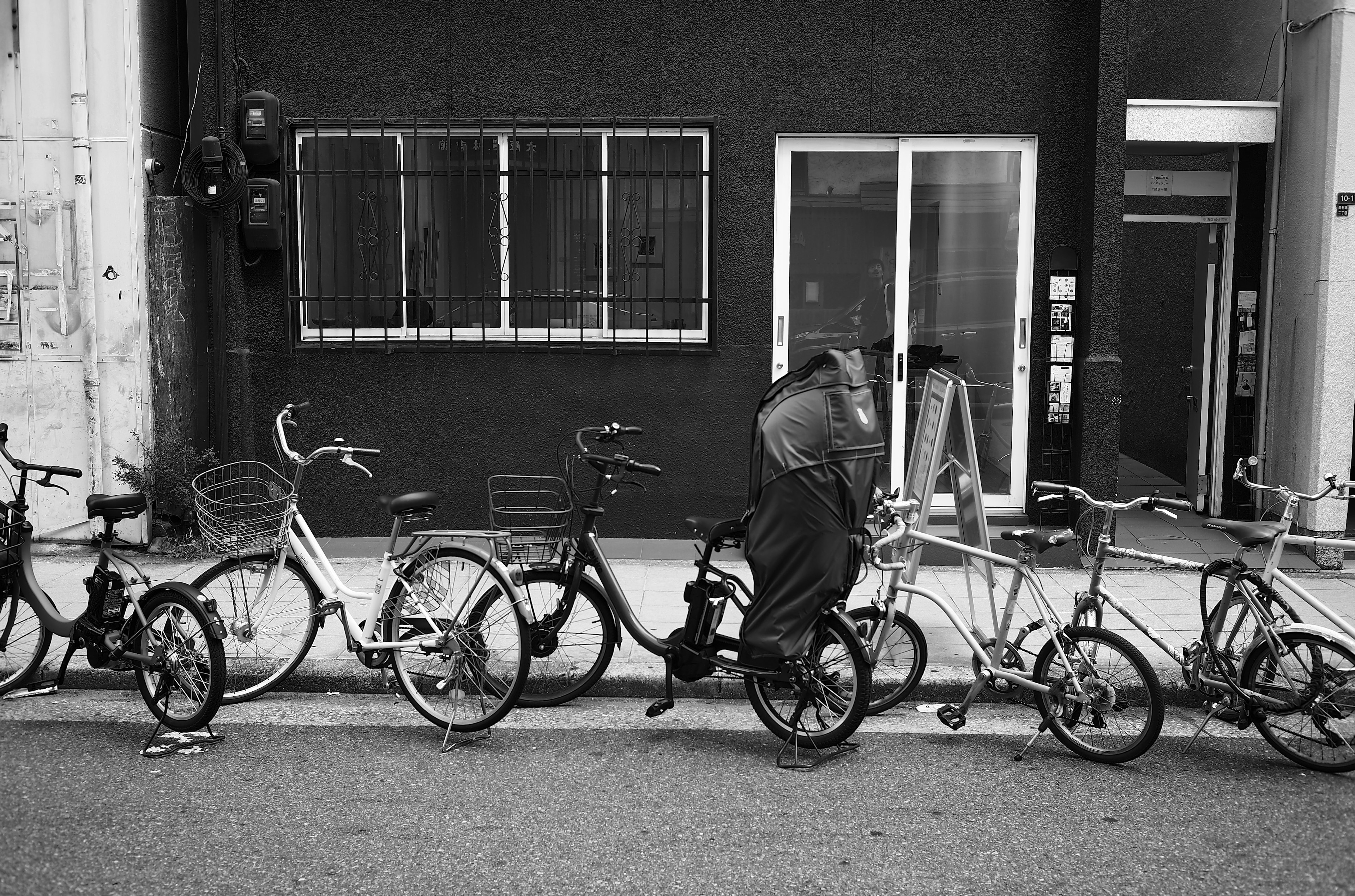 Bicycles lined up in front of a black wall with a person riding a bike