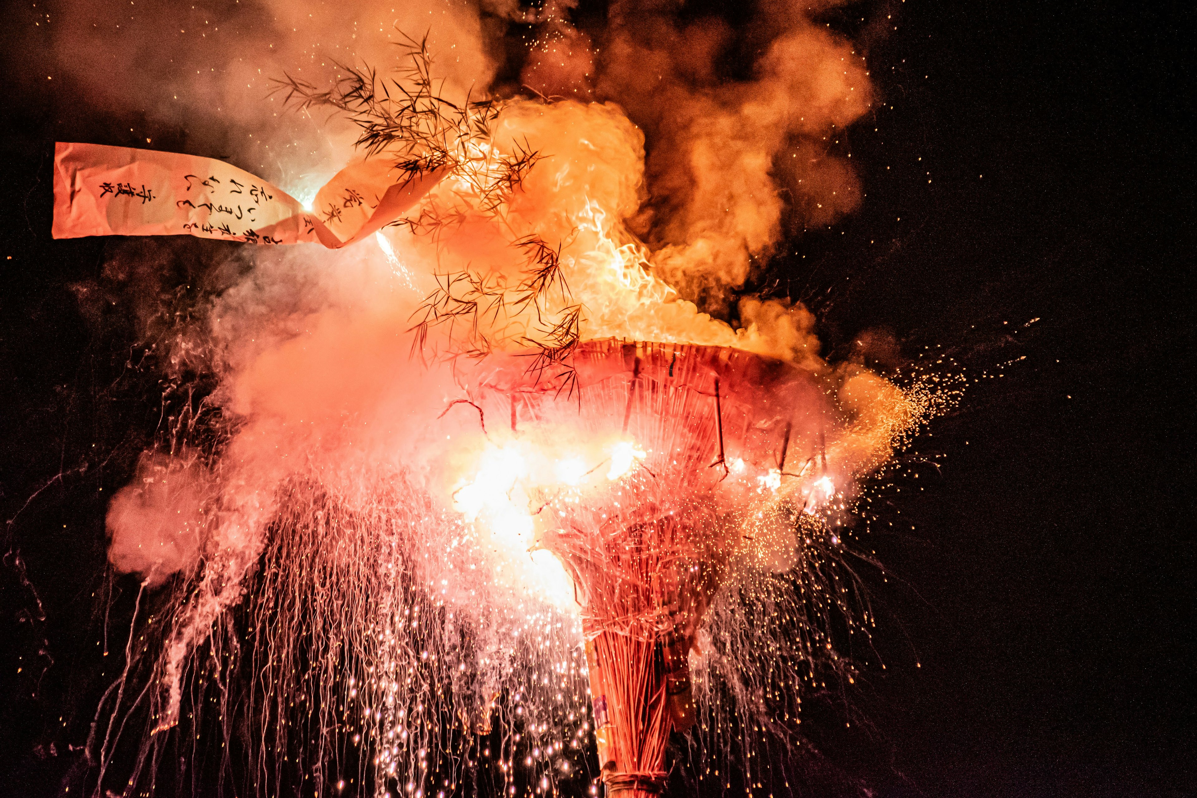 A large firework display with sparks and smoke against the night sky