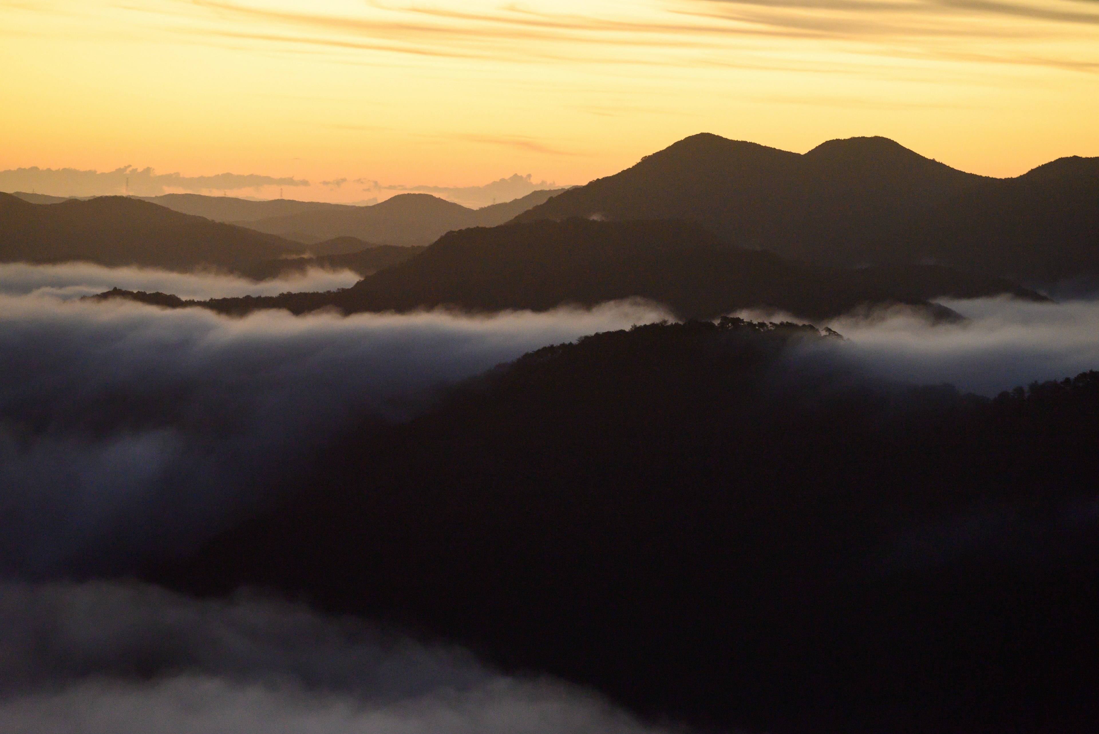 山々のシルエットが美しい夕焼けの空と雲の海に包まれた風景