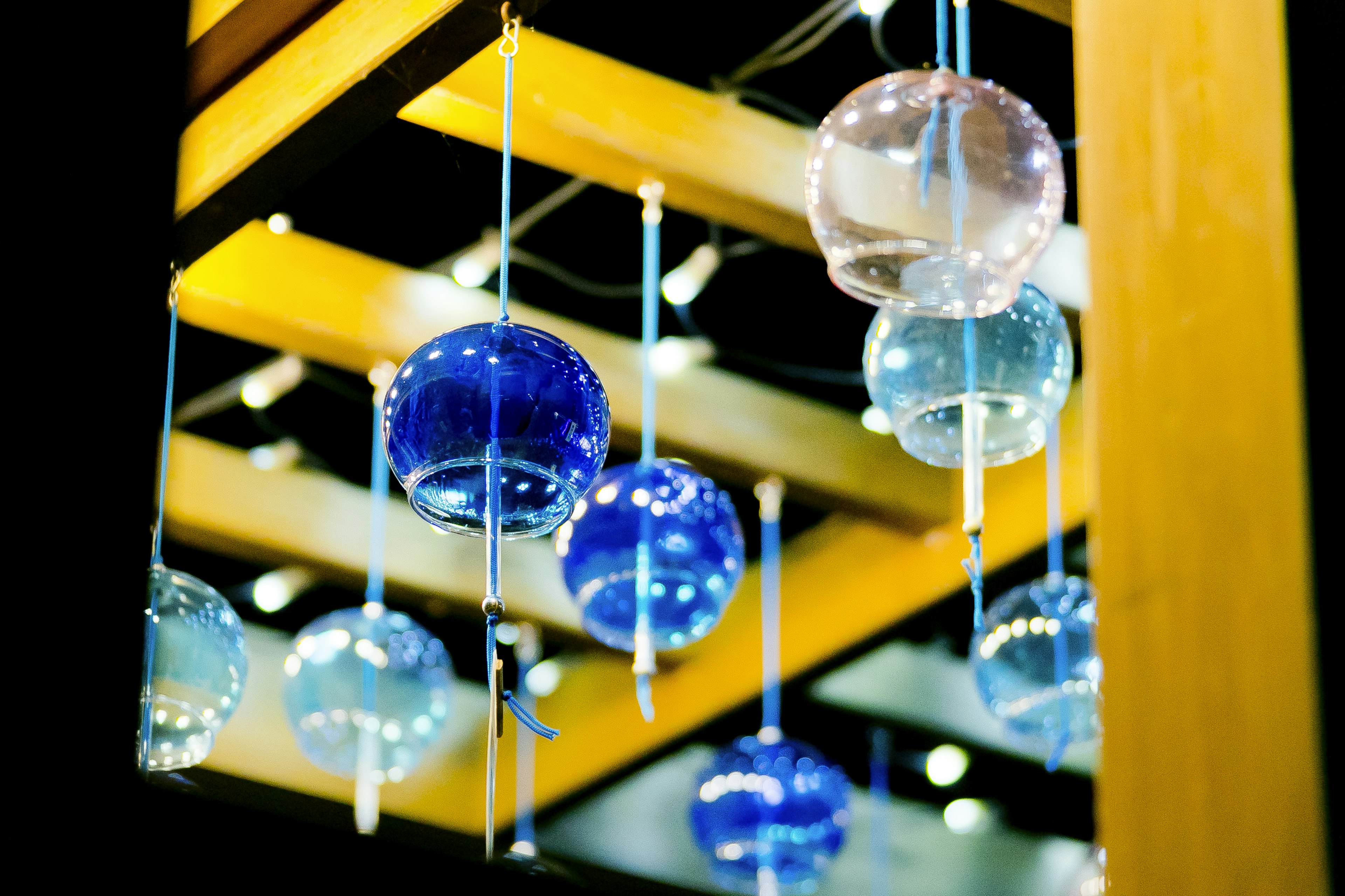 Blue and clear glass orbs hanging from a wooden structure