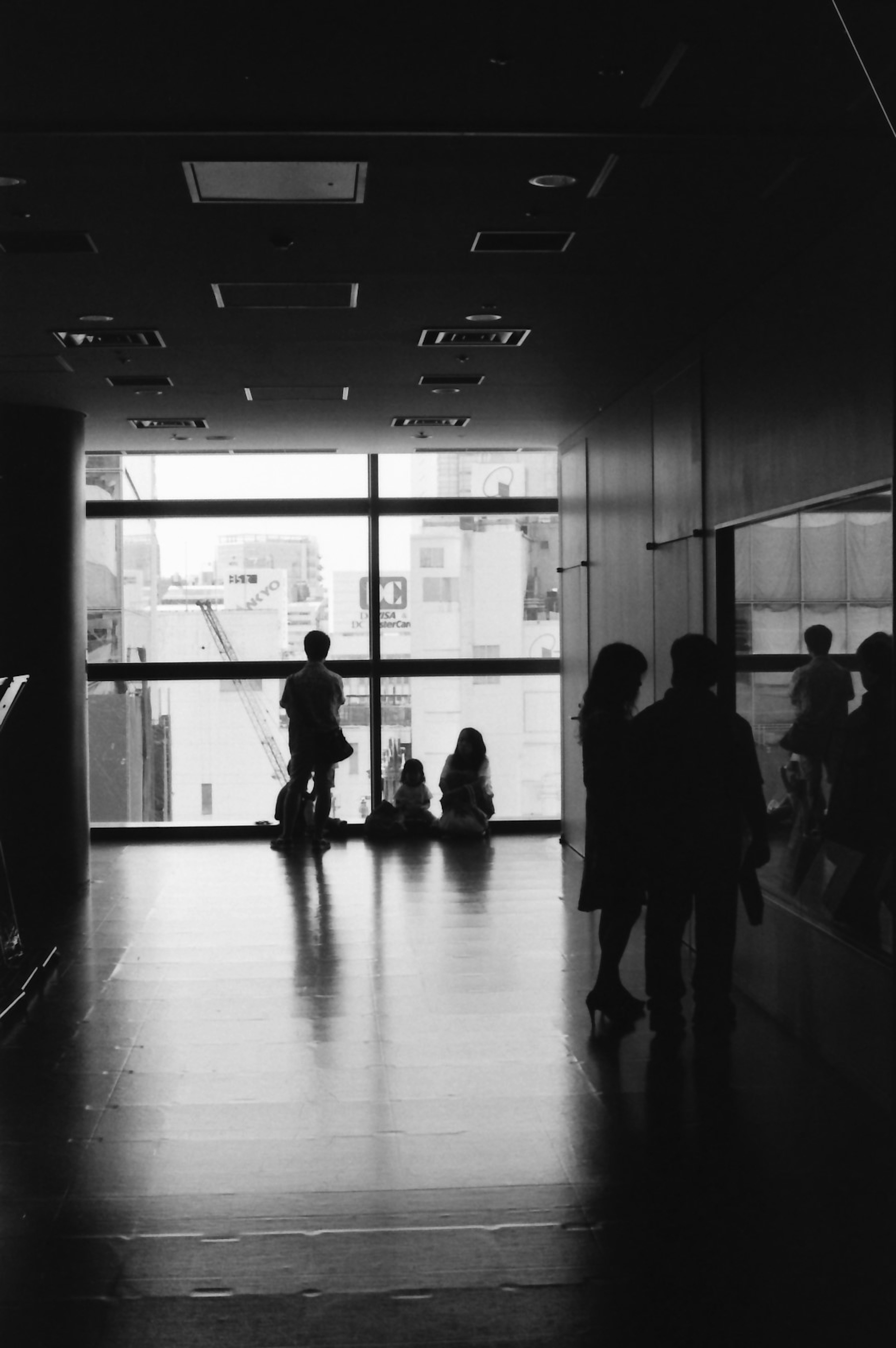 Silhouettes de personnes debout près d'une fenêtre dans un espace en noir et blanc