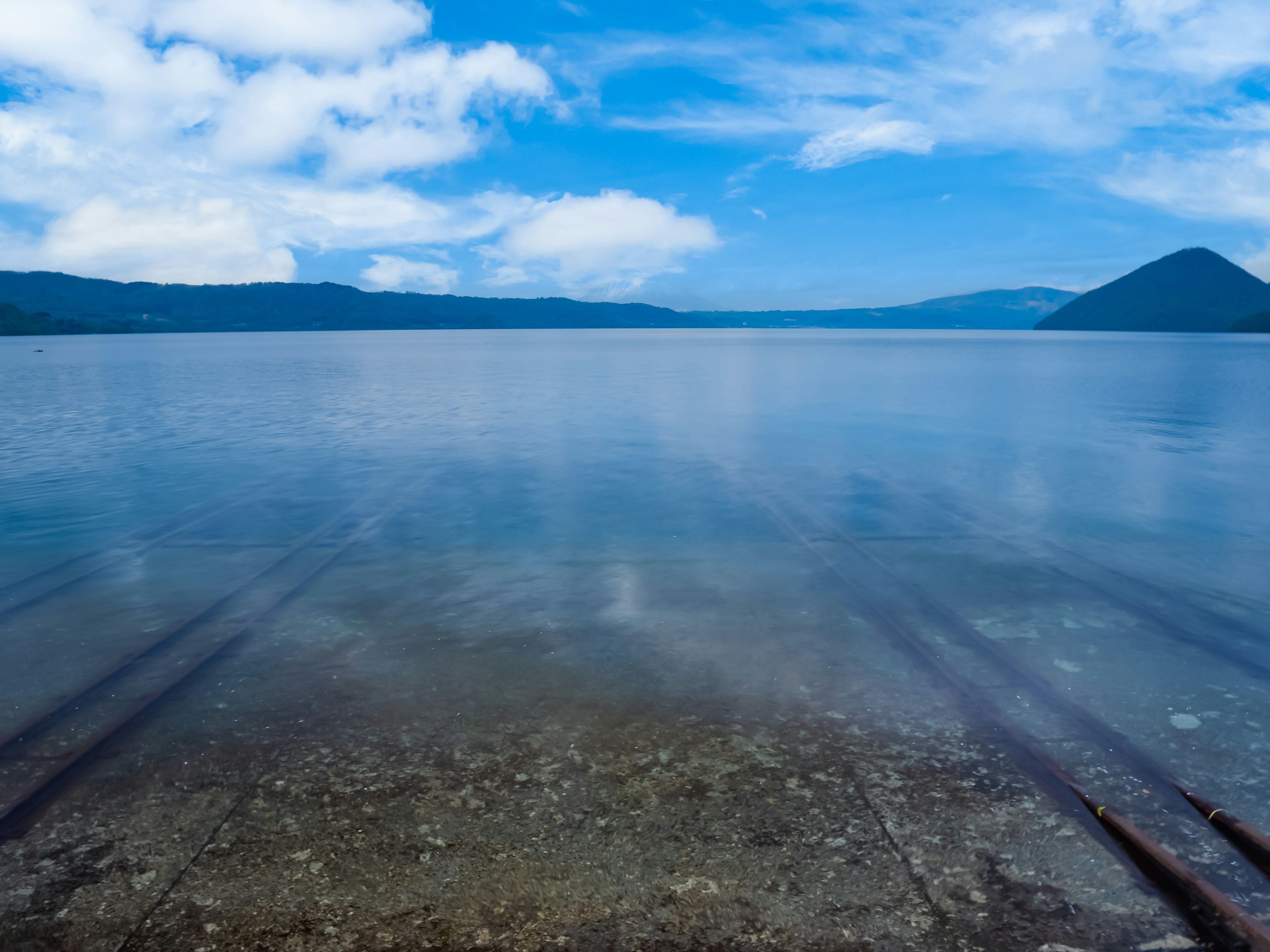 Vista serena di un lago con acqua blu chiara e cielo montagne sullo sfondo