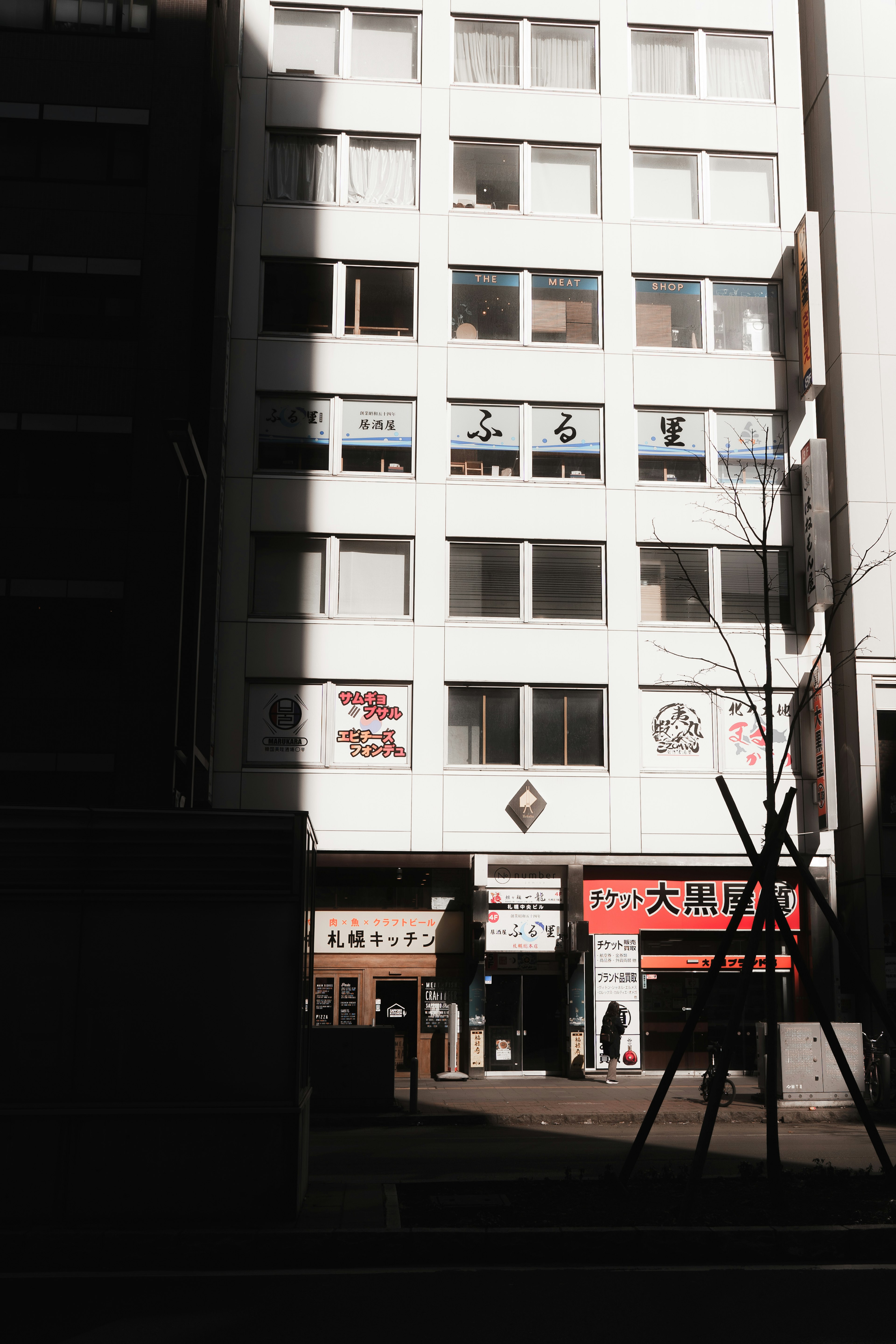 Vue de rue avec un bâtiment blanc et des enseignes commerciales