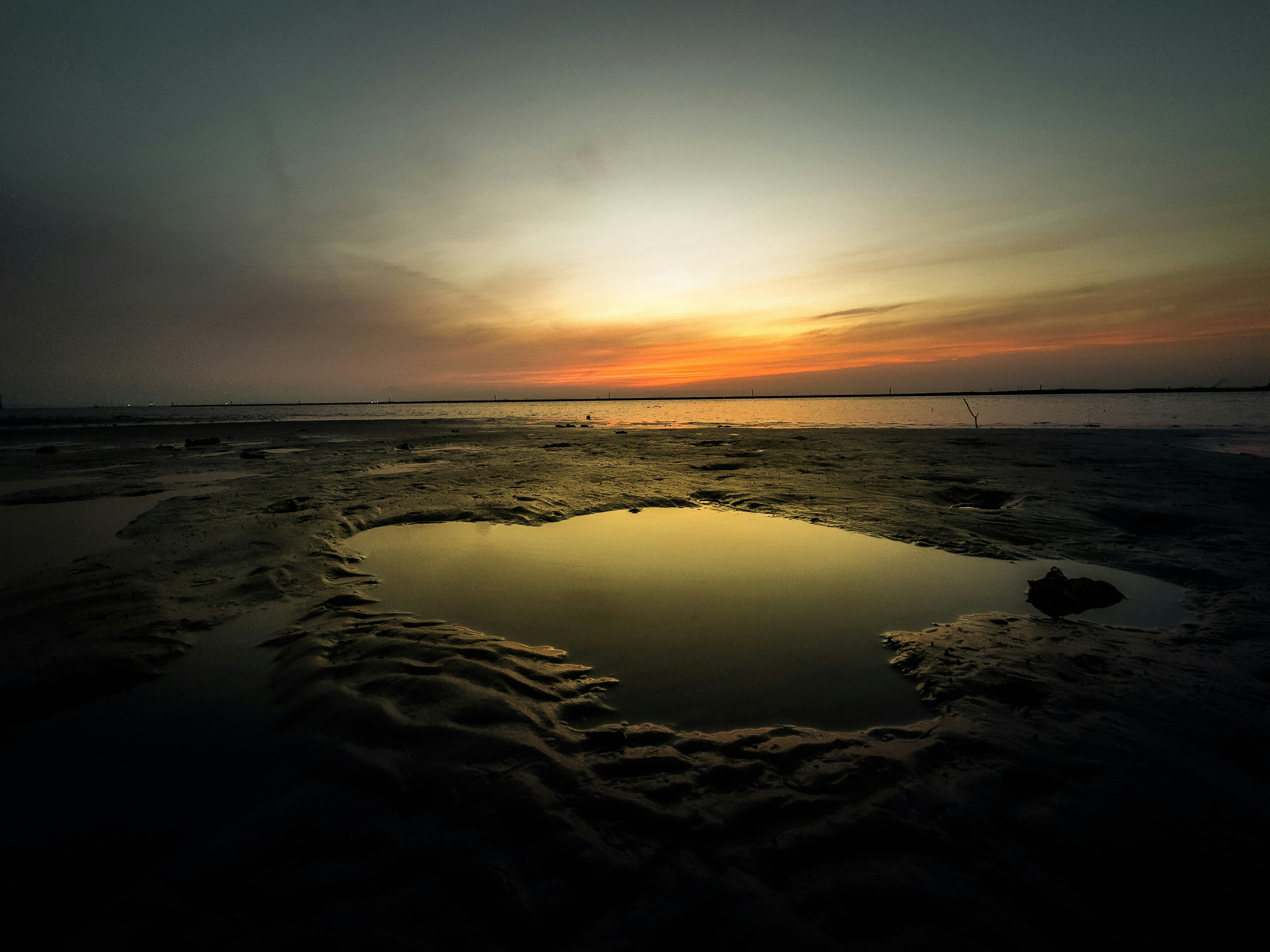 Escena de playa tranquila con reflejo del atardecer en charcas de marea