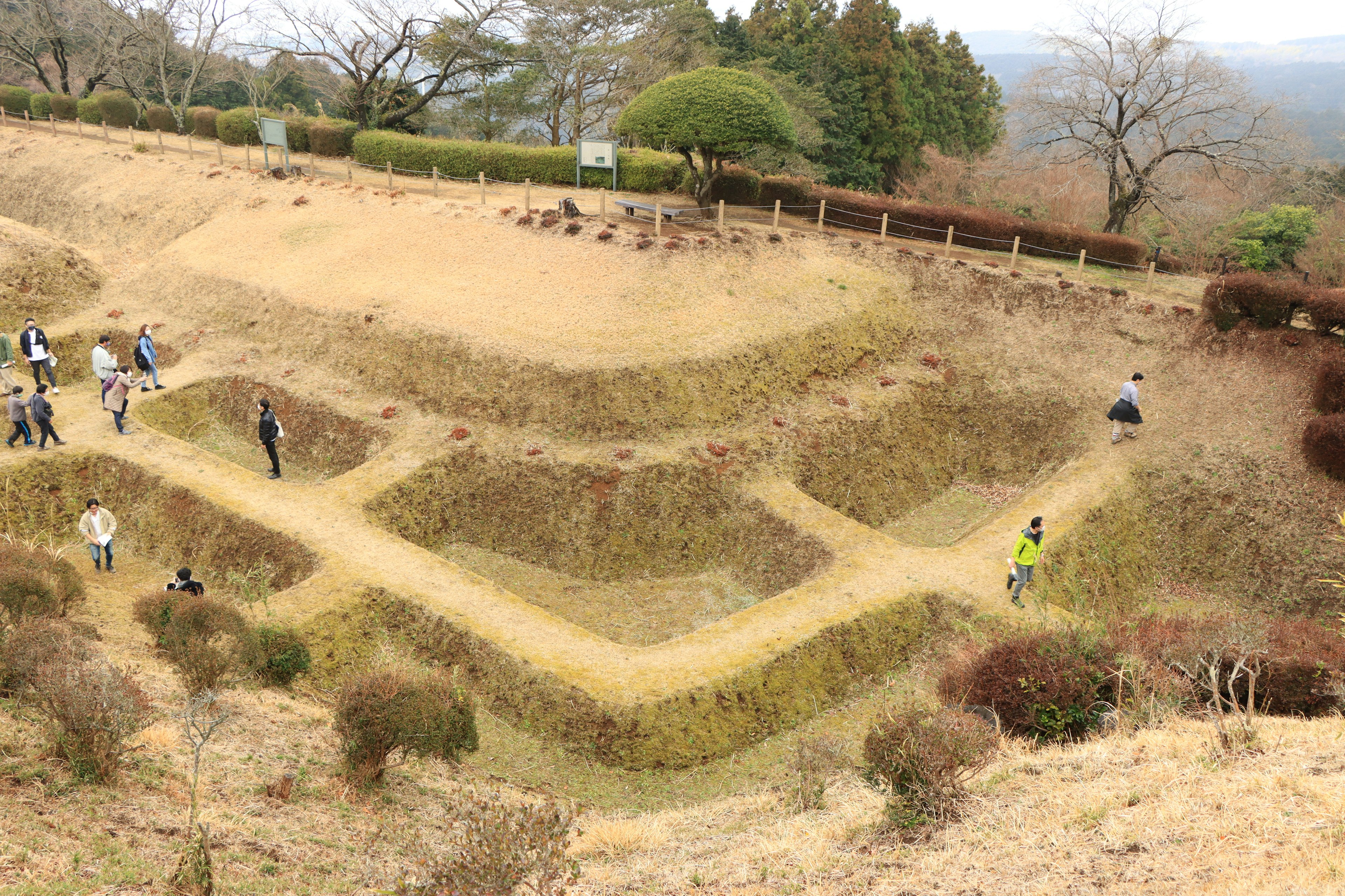 Landscape of ancient ruins with people walking paths and vegetation