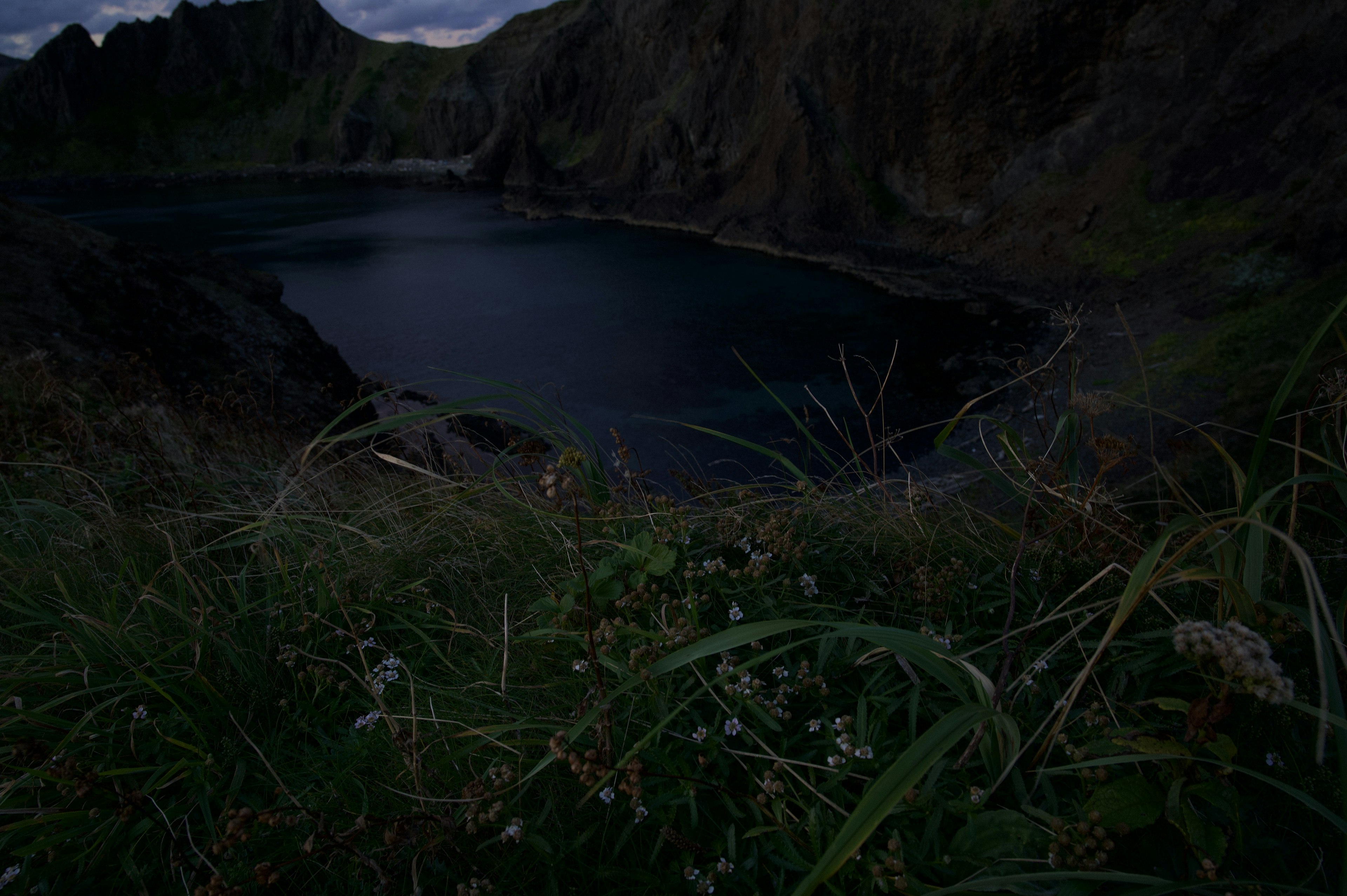 Lac sombre entouré de falaises et d'herbe