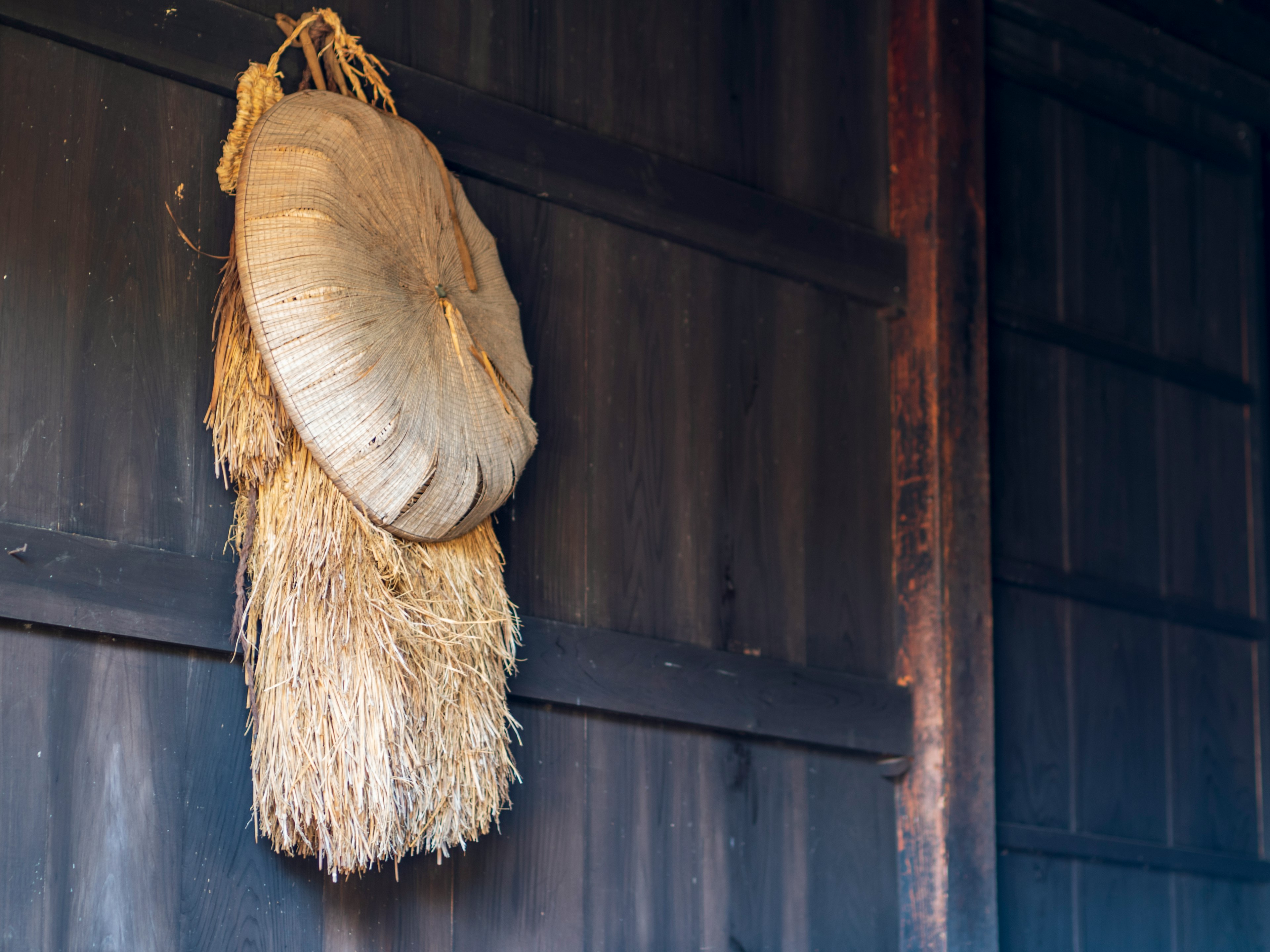 Un sombrero de paja y decoración de espigas colgando en una pared