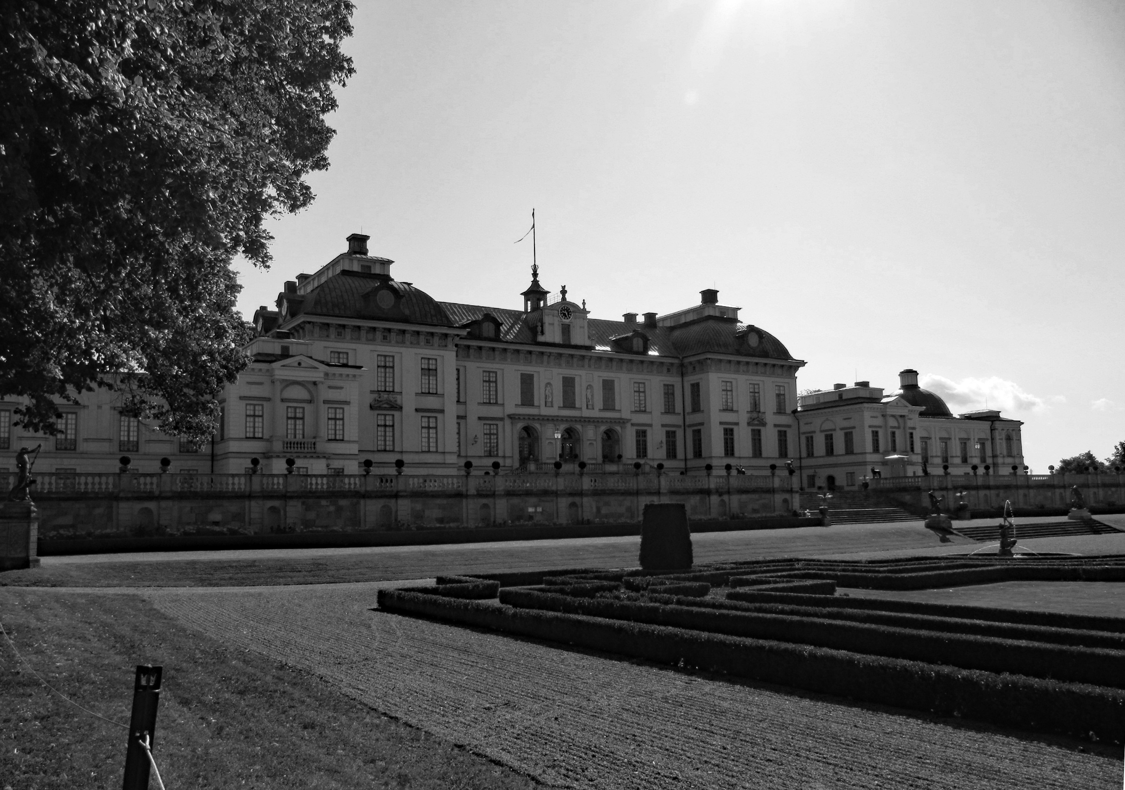 Vista en blanco y negro de un castillo con jardines bien cuidados