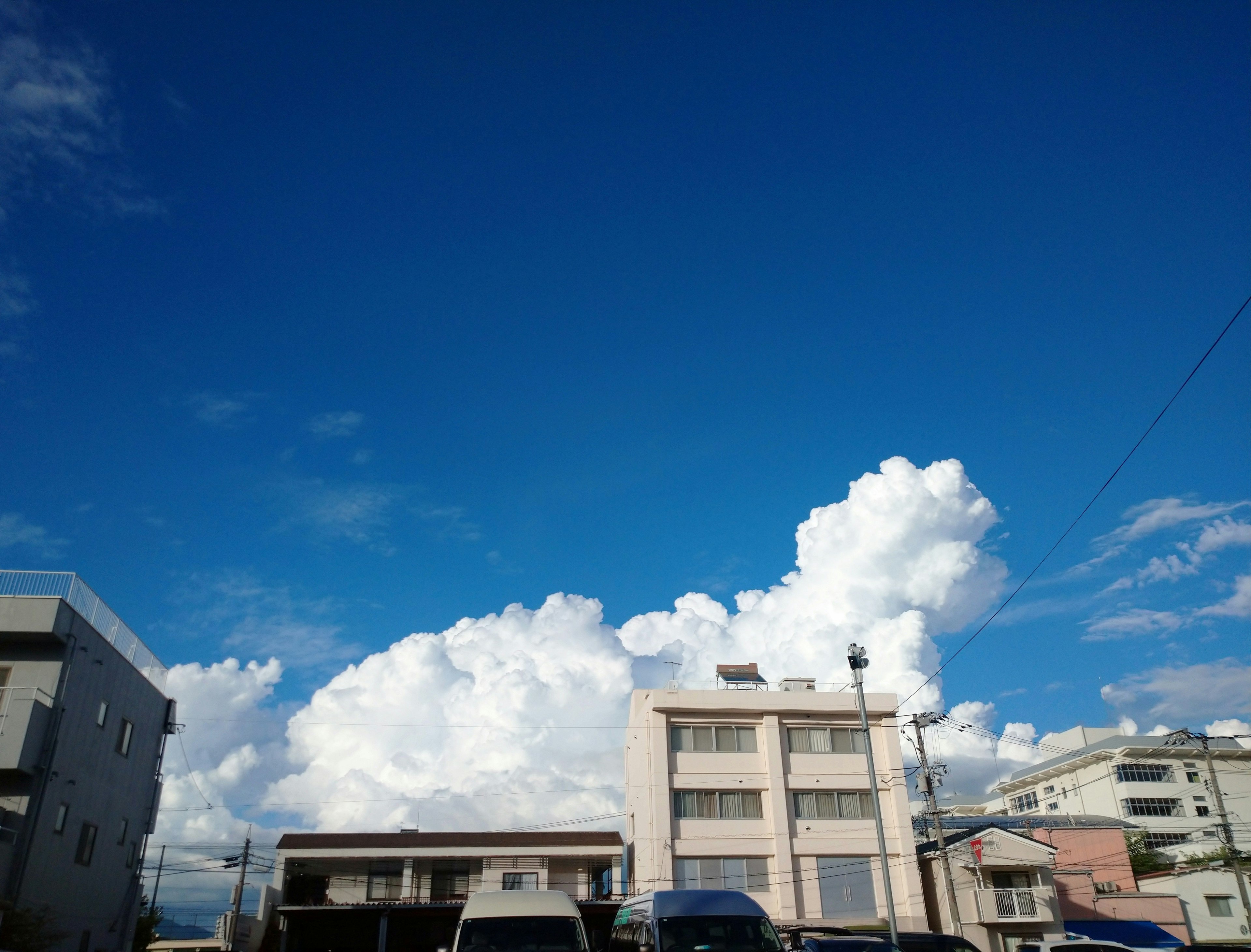 Langit biru cerah dengan awan putih berbulu di atas bangunan