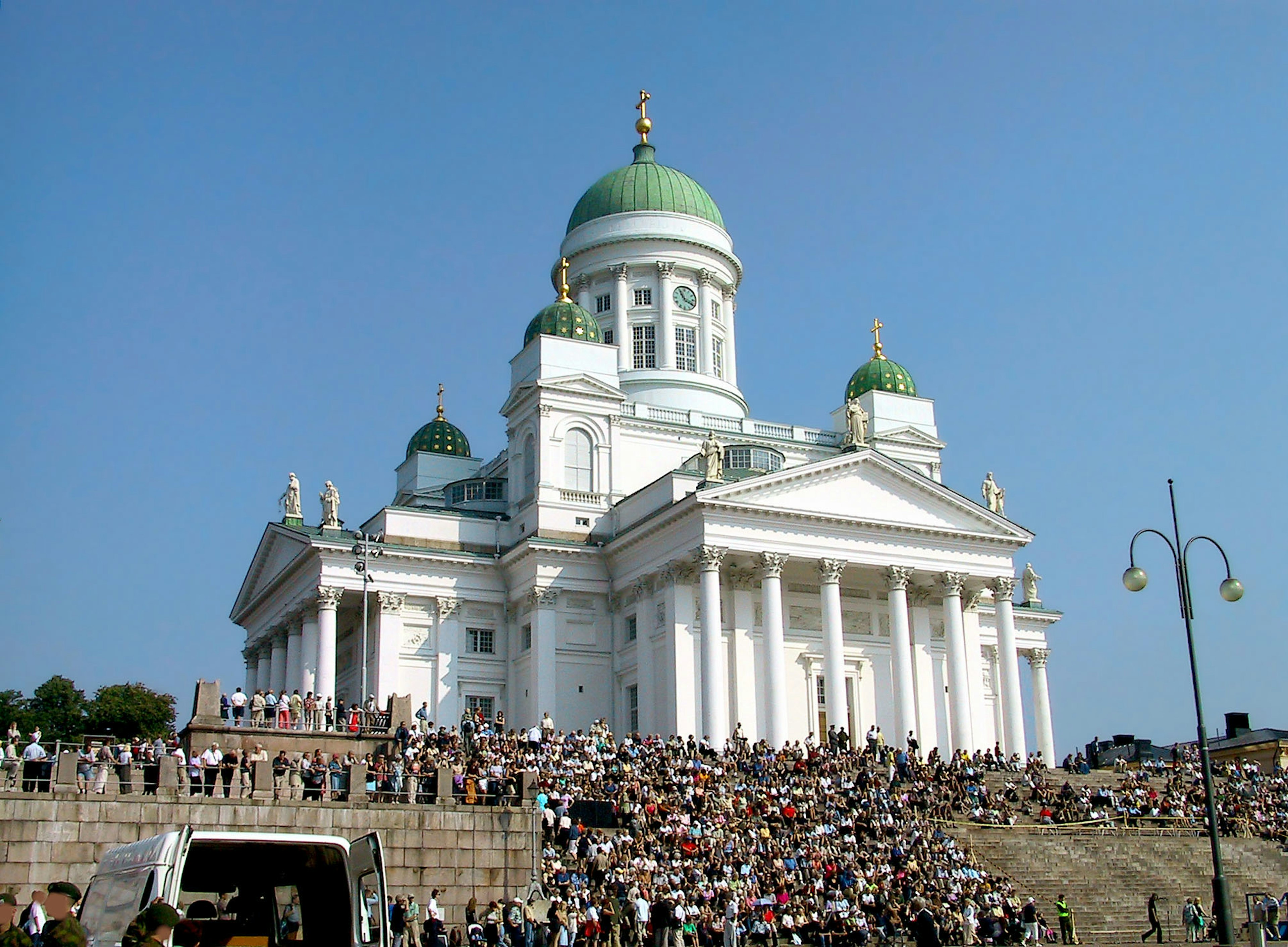 Catedral de Helsinki con elegante arquitectura y cúpulas verdes rodeada de una gran multitud