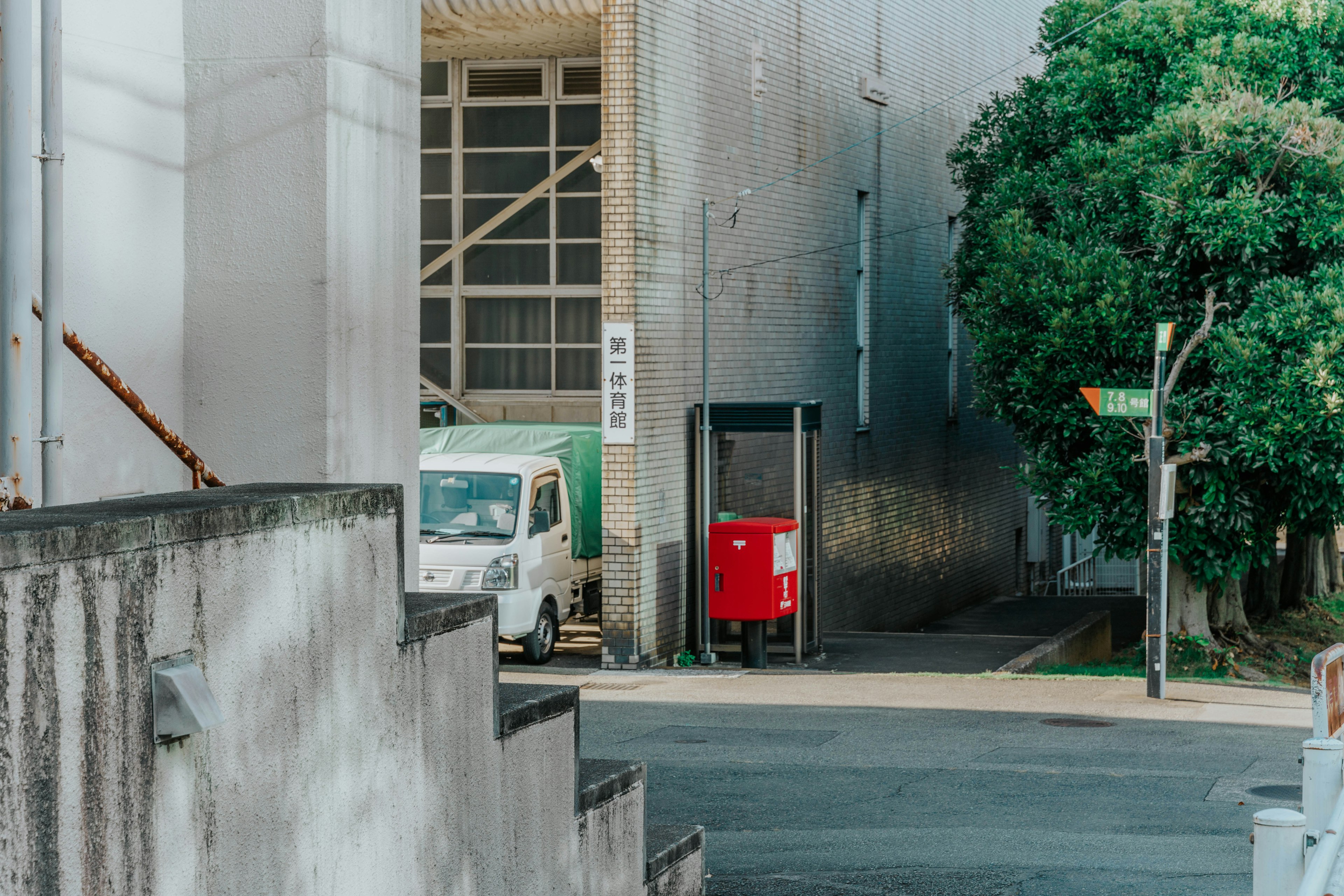 Esquina de la calle con un buzón rojo y un vehículo blanco