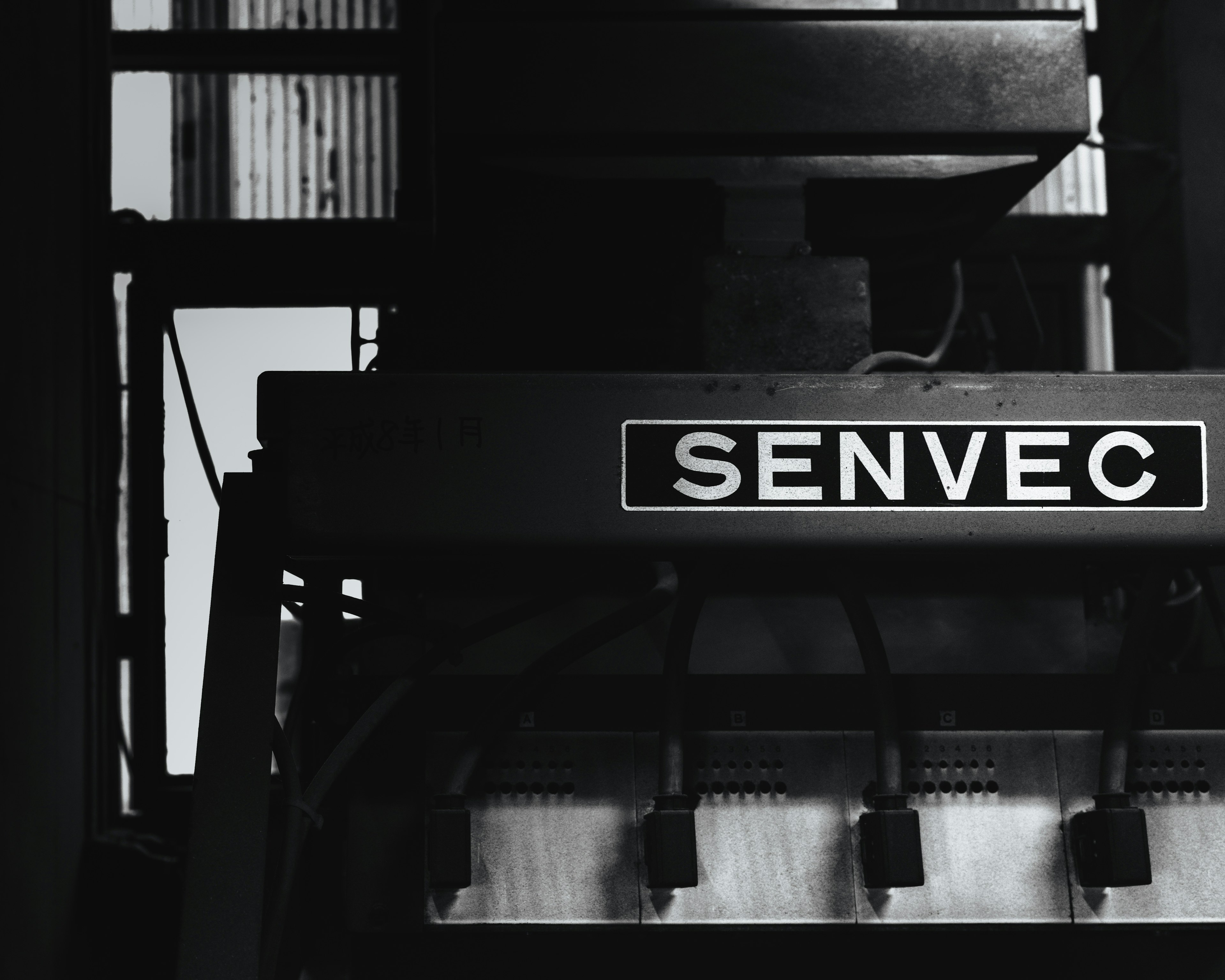 Part of a machine featuring the SENDEC logo against a black and white background