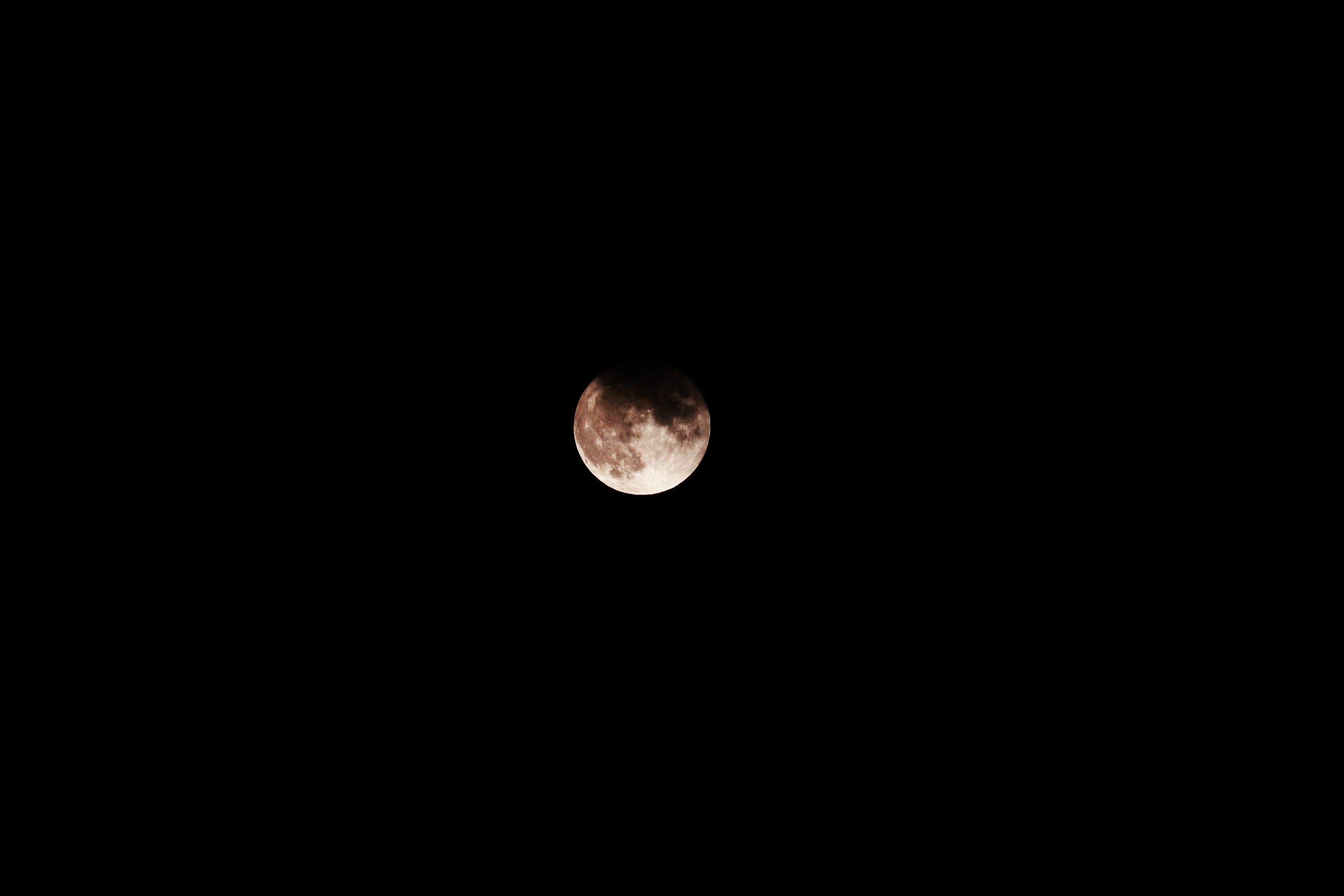 Tampilan rinci bulan dengan kawah dan bayangan di latar belakang gelap