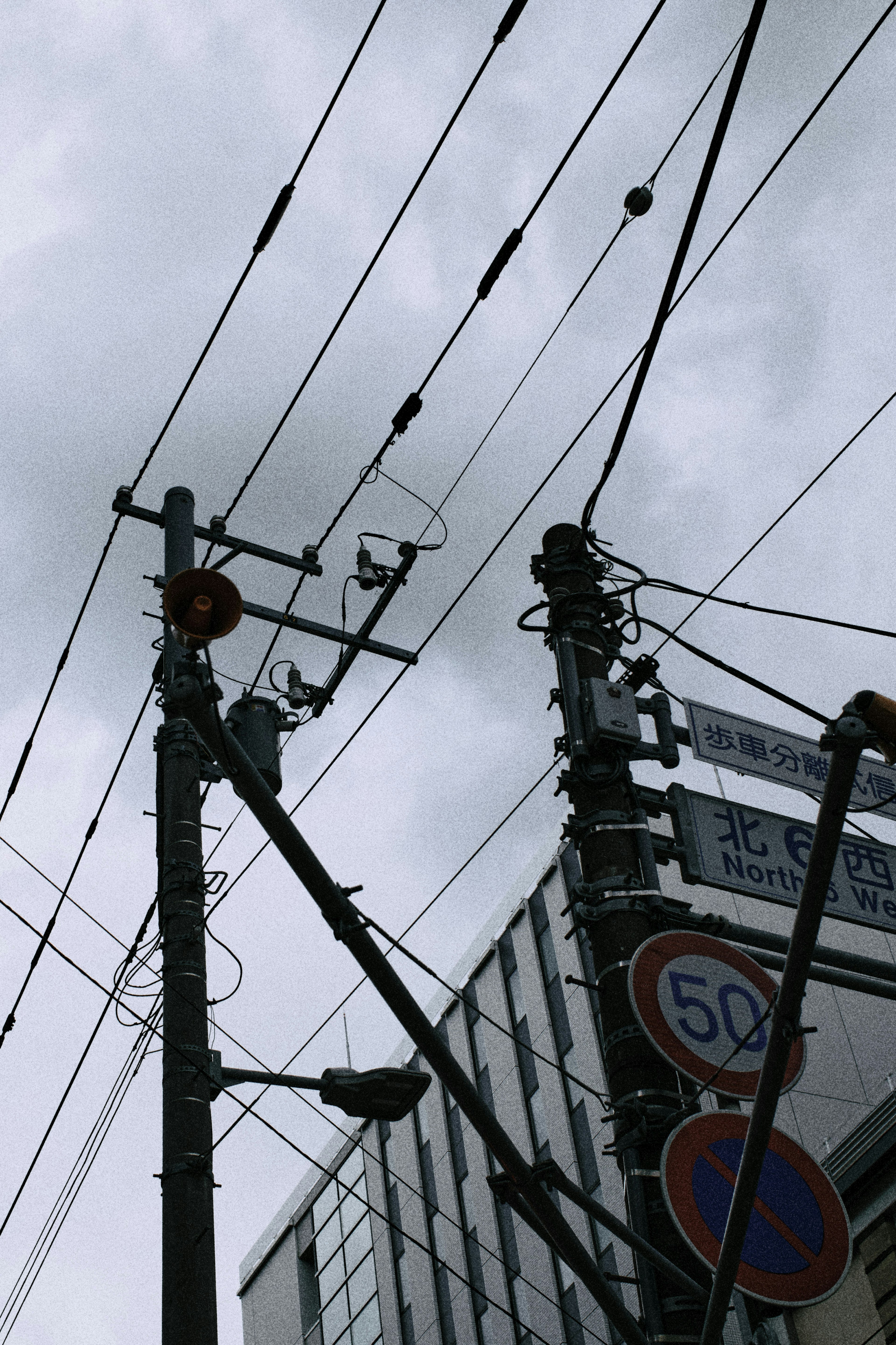 Intersection view of utility poles and wires under a cloudy sky