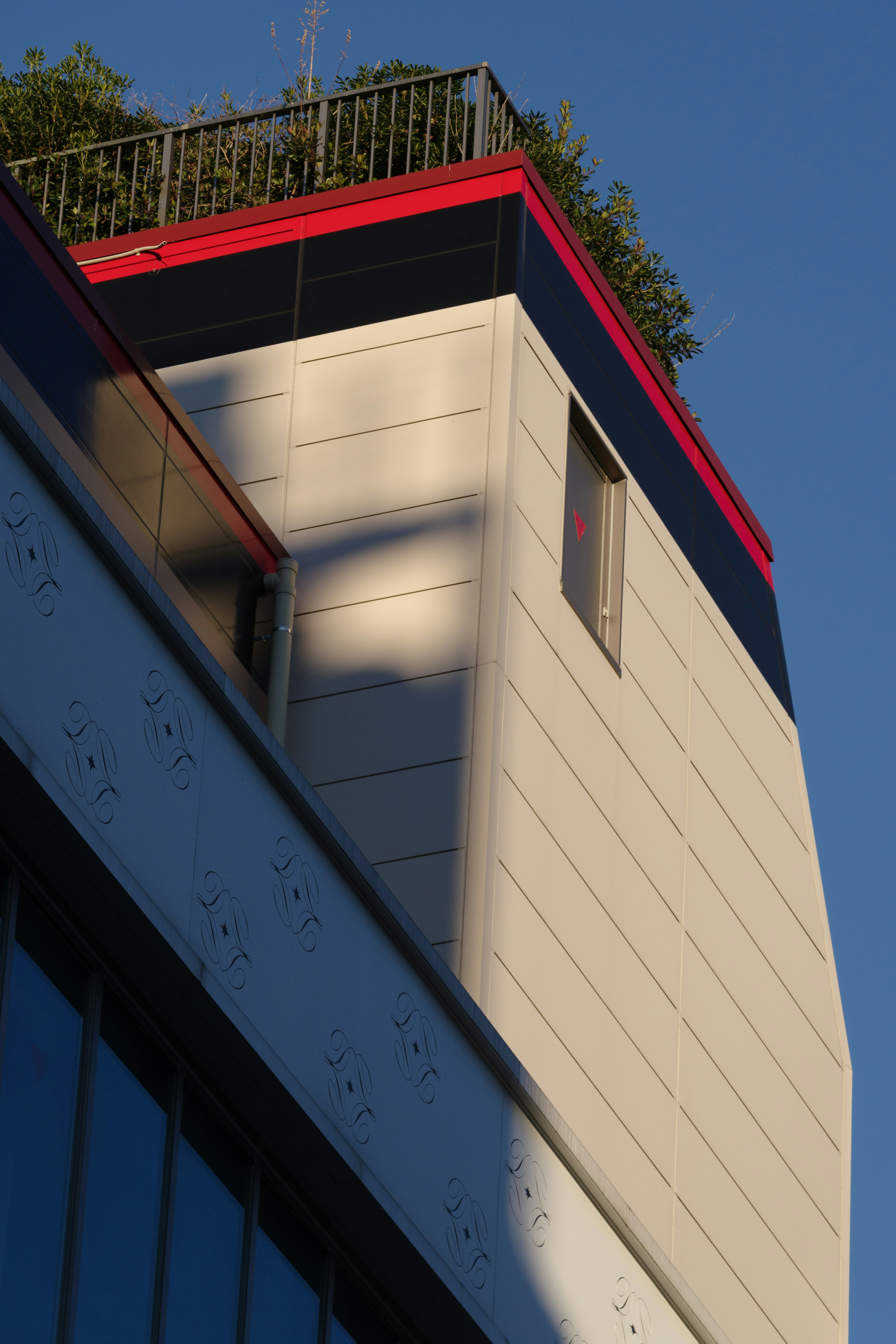 Corner of a modern building with a red trim under a blue sky