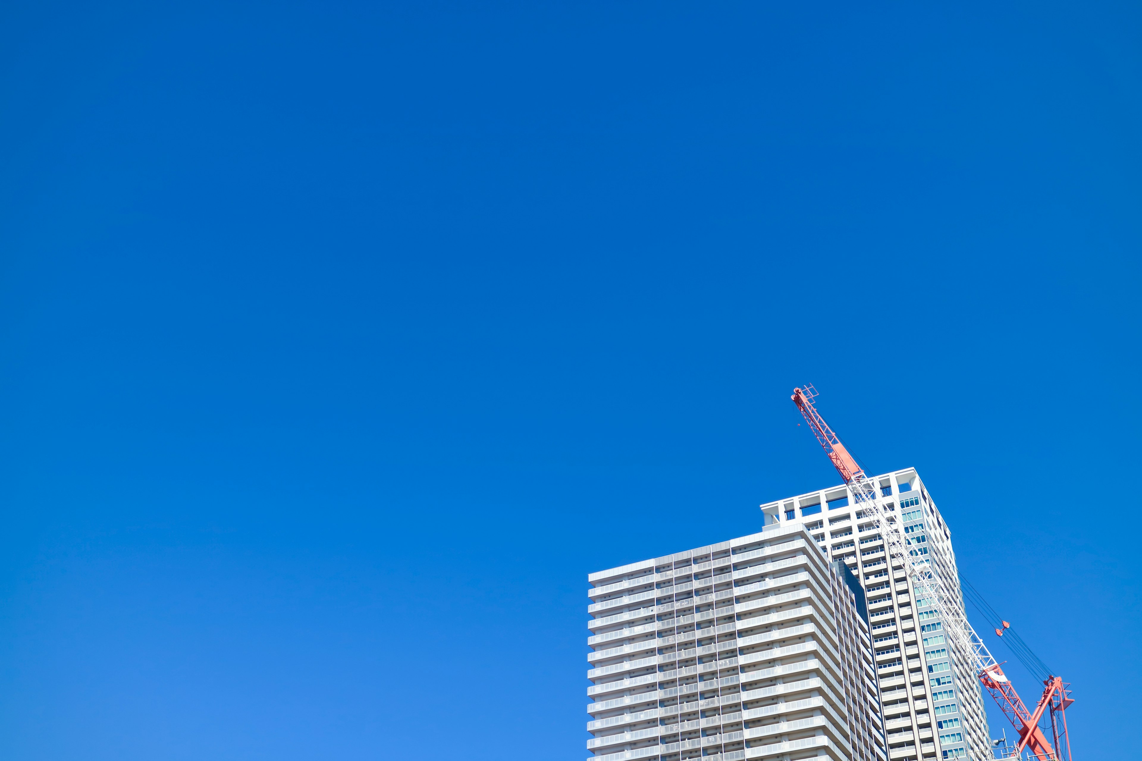 Edificio de gran altura en construcción con grúa bajo un cielo azul claro