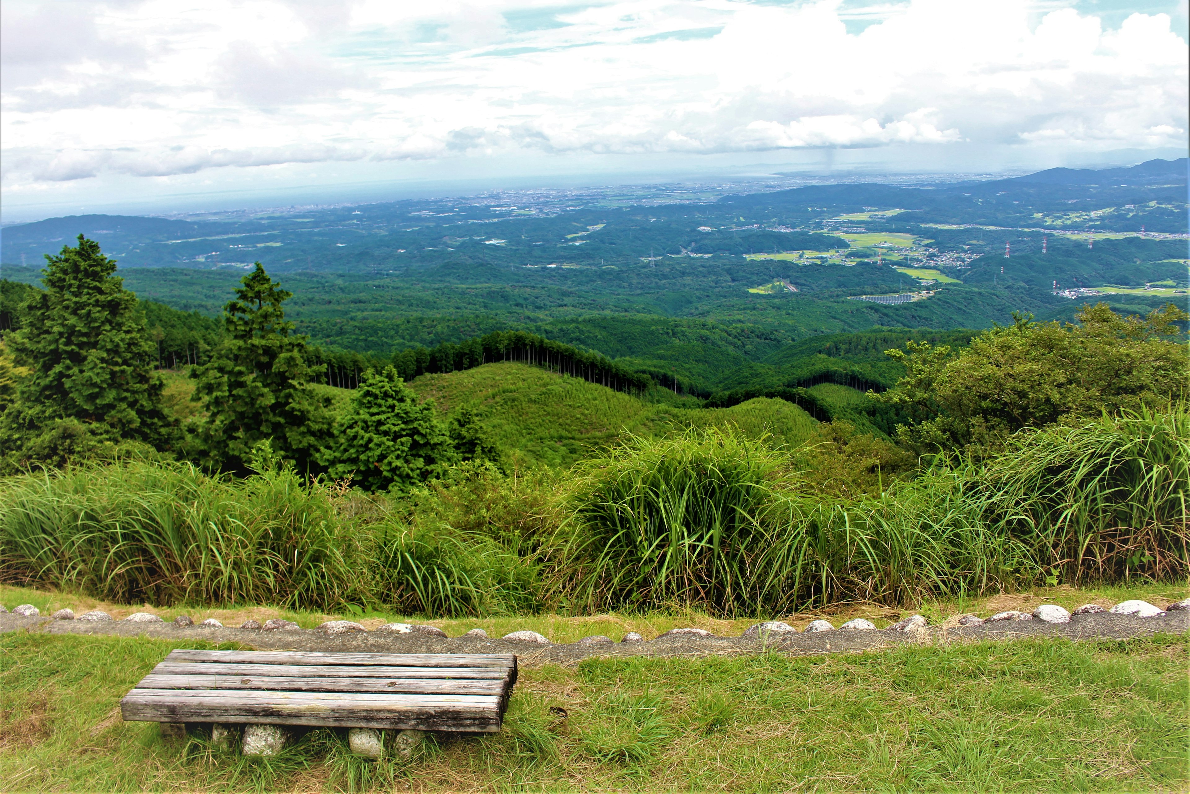 Pemandangan indah dari bangku yang menghadap perbukitan subur dan gunung yang jauh