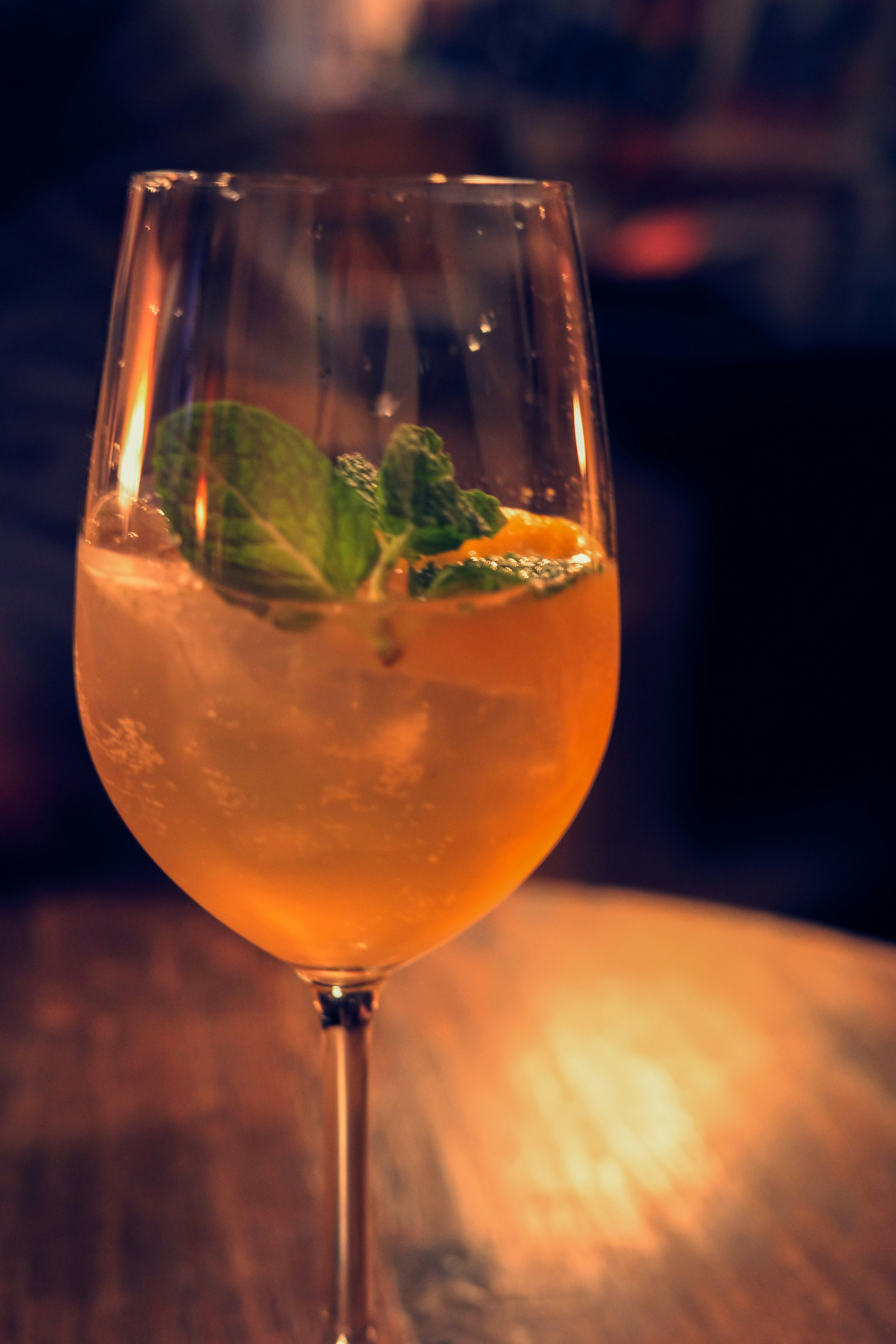 Orange cocktail garnished with mint leaves and orange slices in a glass