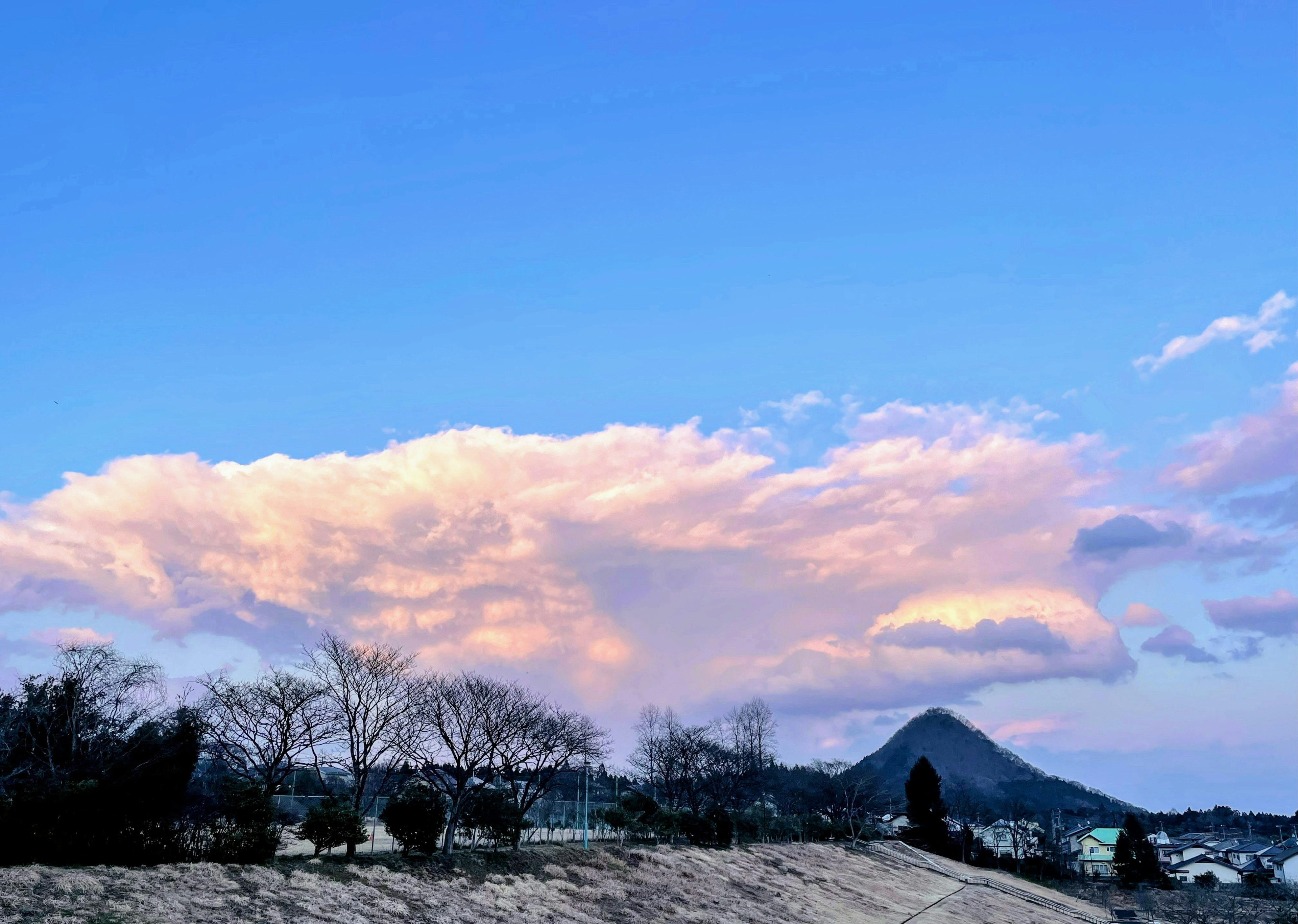 Landscape featuring a blue sky with clouds and a mountain