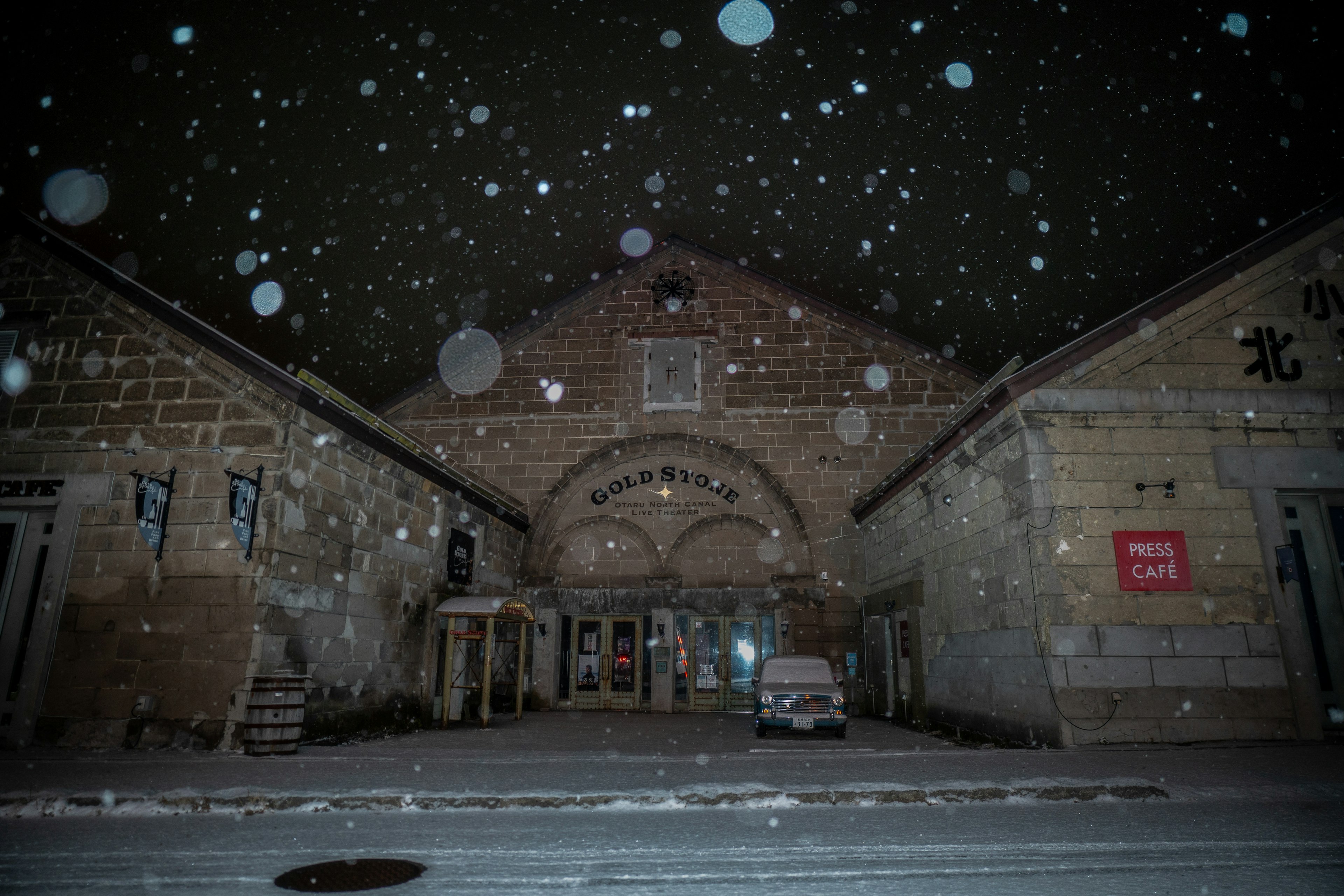 Exterior de un edificio antiguo durante una nevada nocturna con señalización brillante