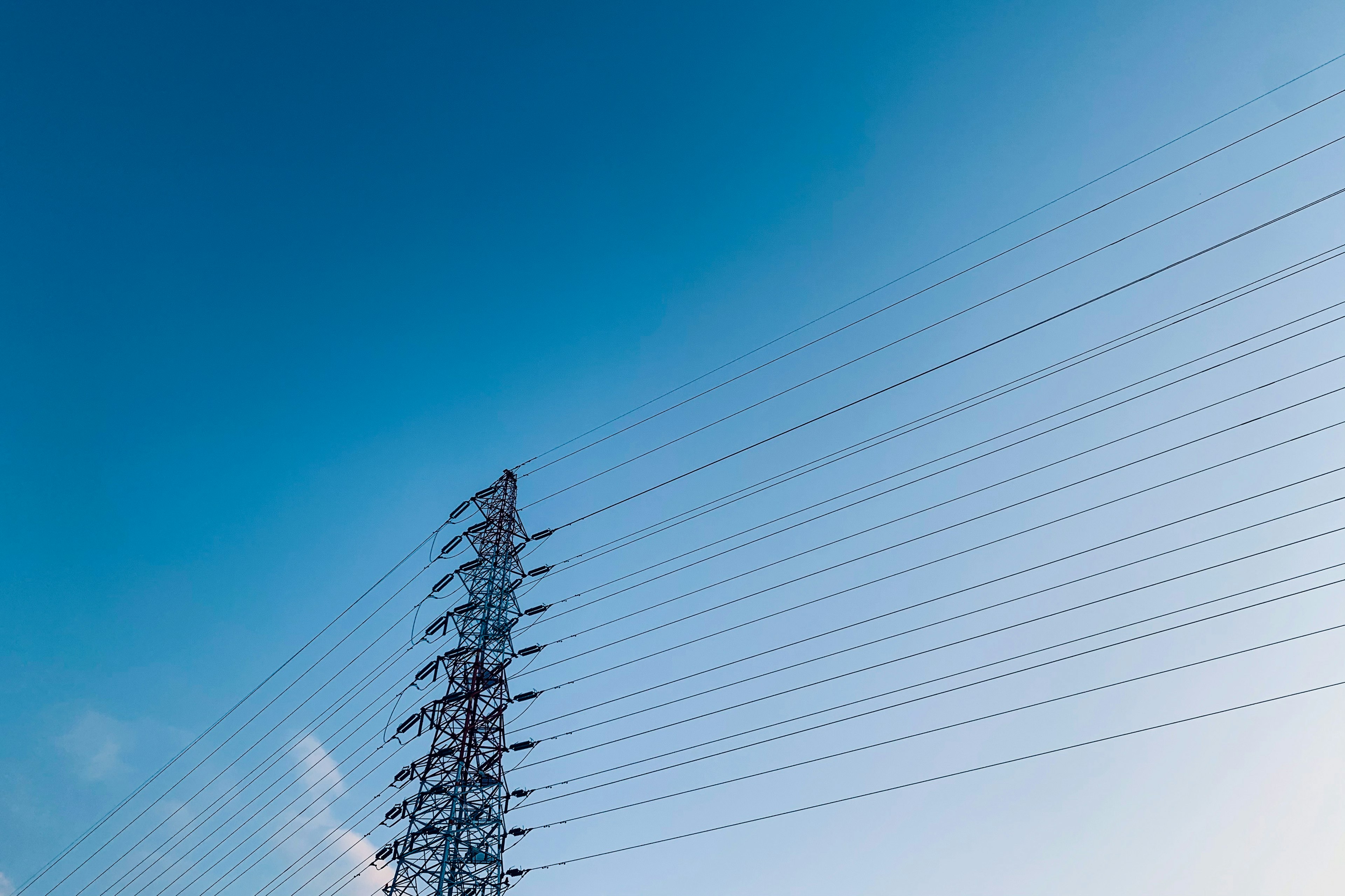 Torre de energía contra un cielo azul con líneas eléctricas