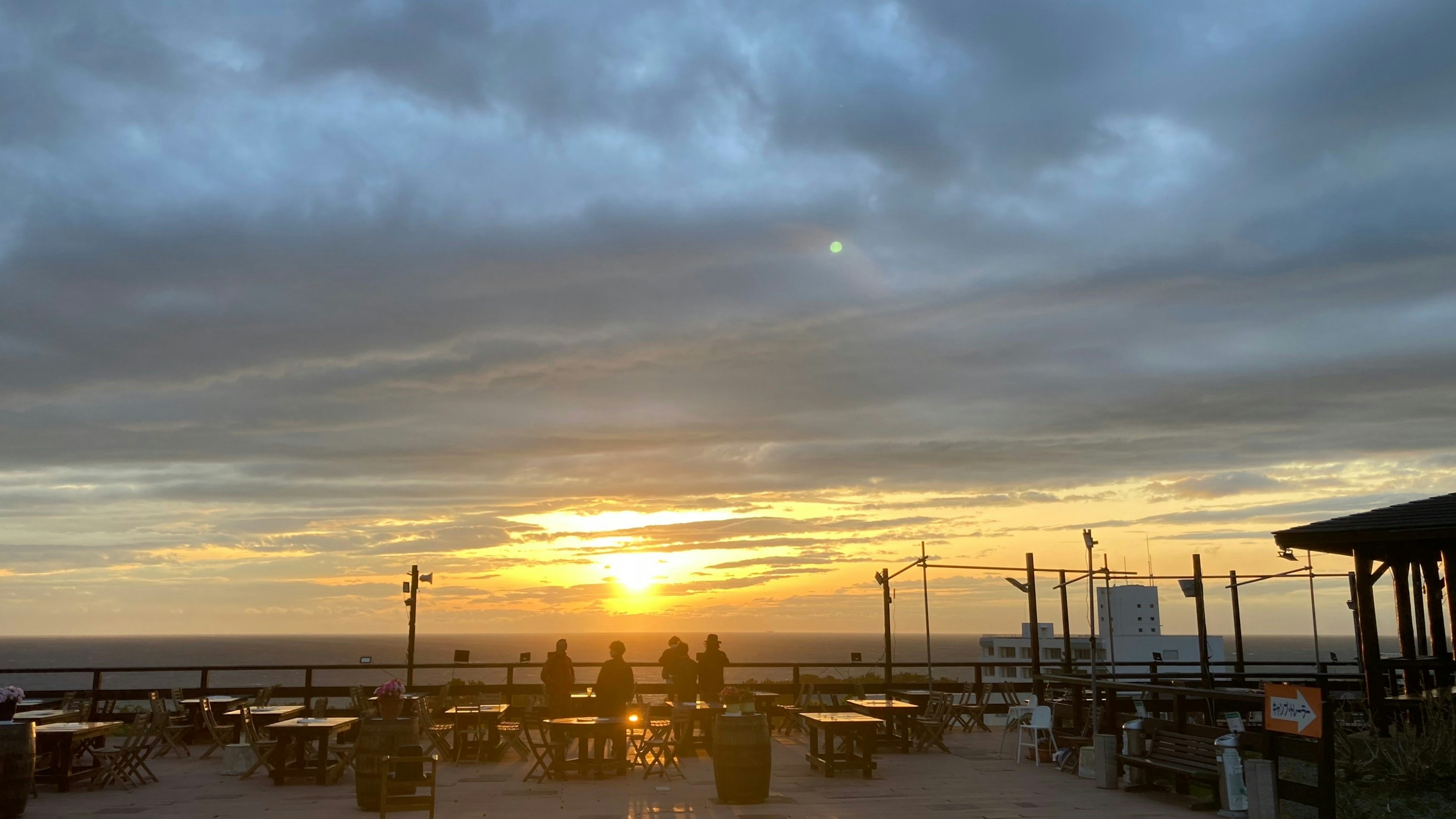 夕日が沈む海辺のテラスで人々が座っている風景