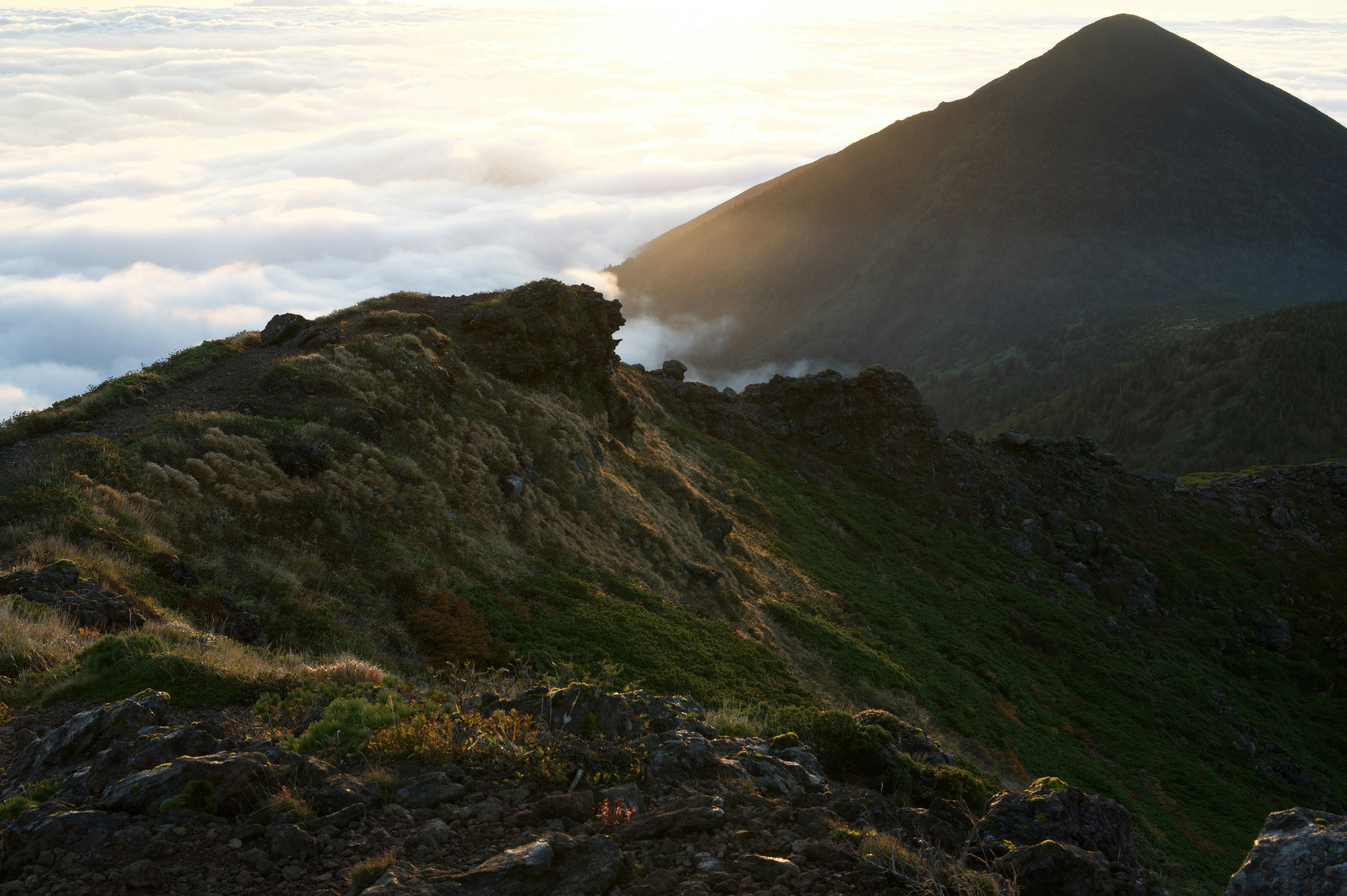 Silhouette de crête de montagne au-dessus d'une couverture nuageuse au coucher du soleil