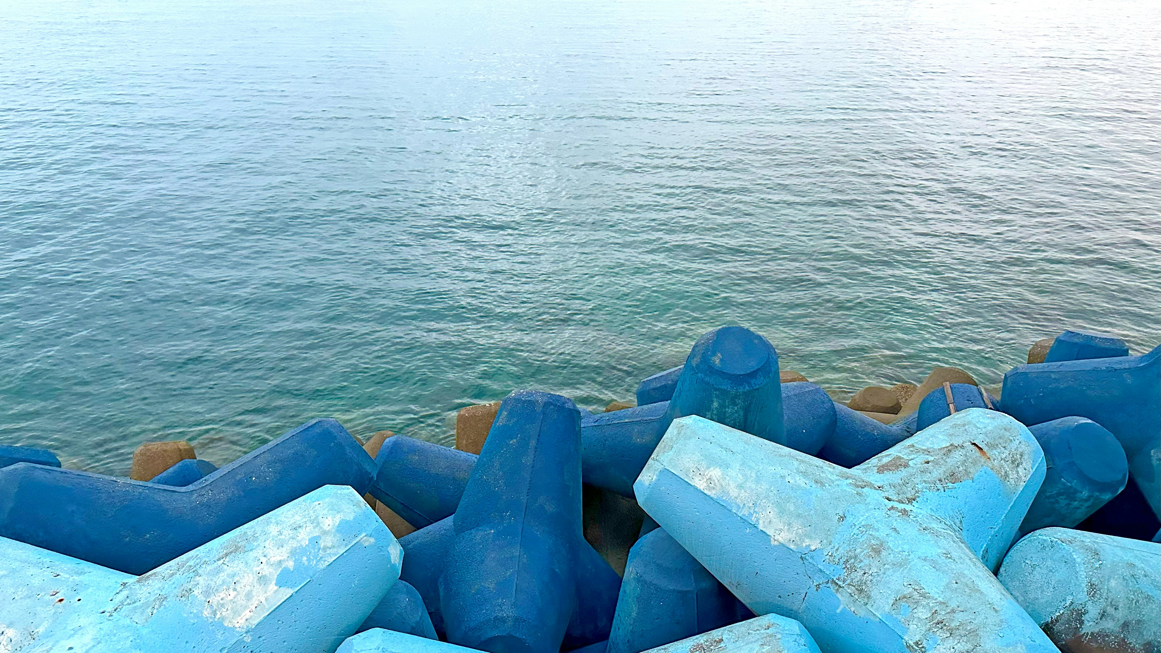 Blocchi di frangiflutti blu con mare calmo sullo sfondo